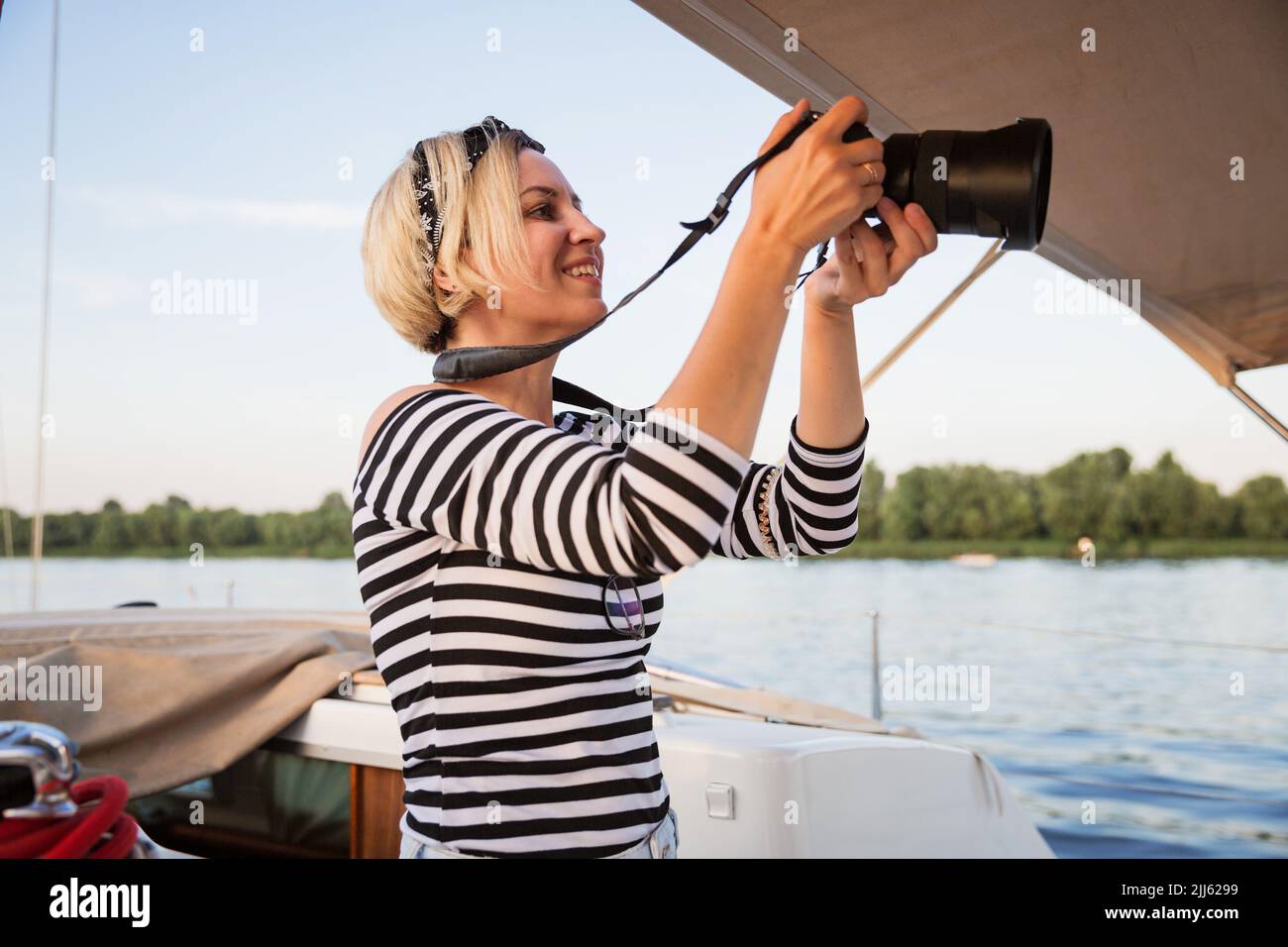 Hübsche Frau mit Kamera, die auf einer Yacht fotografiert Stockfoto