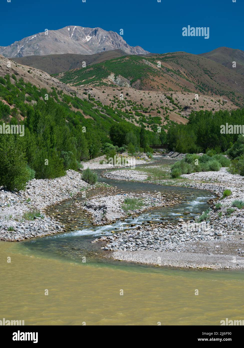 Klares Wasser fließt aus den Bergen. Fluss des sauberen Baches in den schlammigen Fluss. Wasserverschmutzung und Naturkonzept Stockfoto