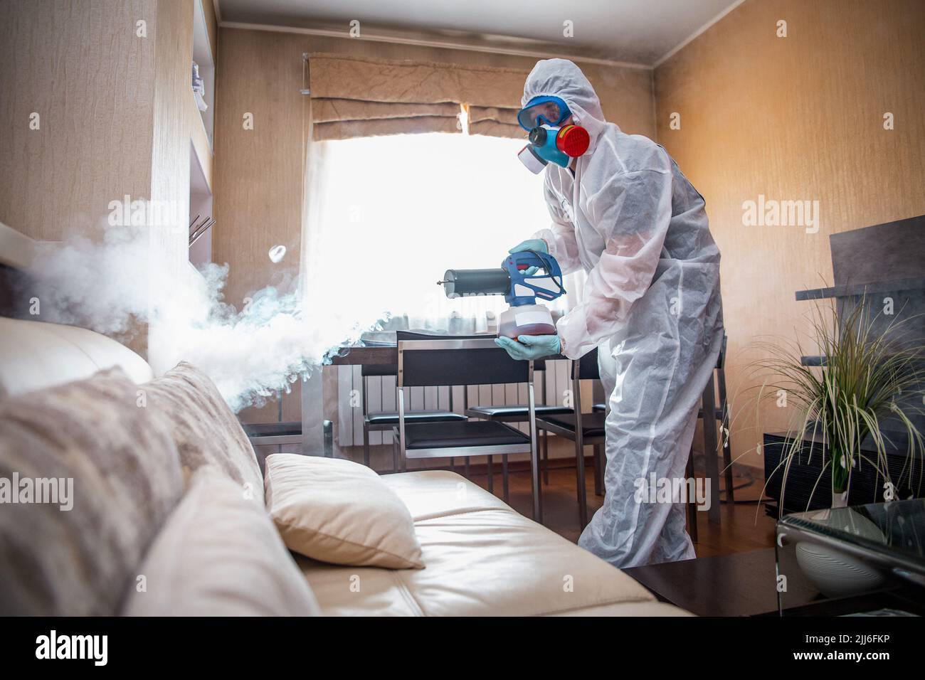 Desinfektion des Raumes gegen Viren. Mann in Quarantänekleidung, der den Raum desinfiziert. Stockfoto