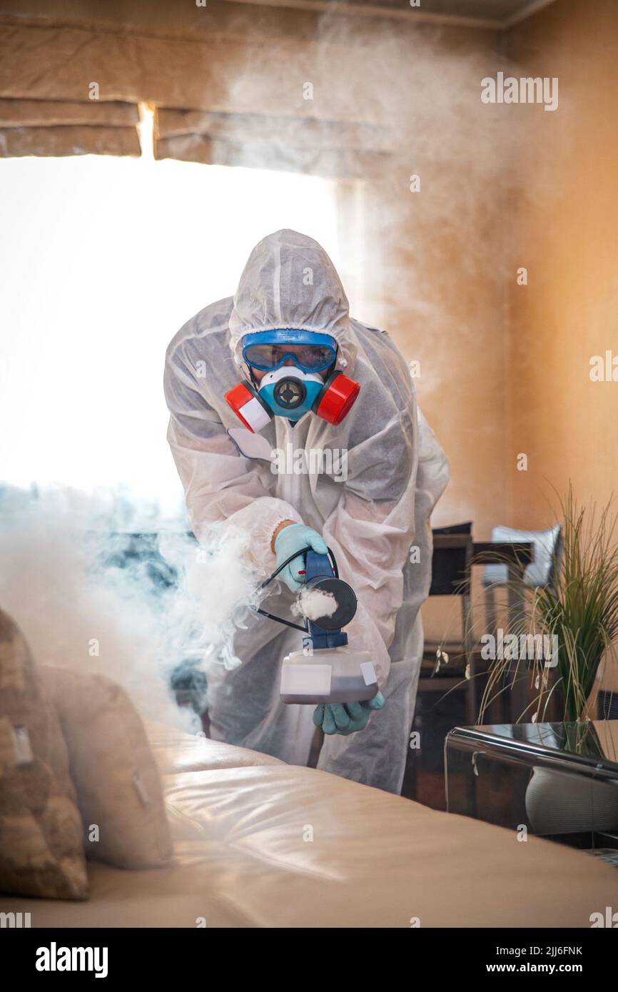 Desinfektion des Raumes gegen Viren. Mann in Quarantänekleidung, der den Raum desinfiziert. Stockfoto