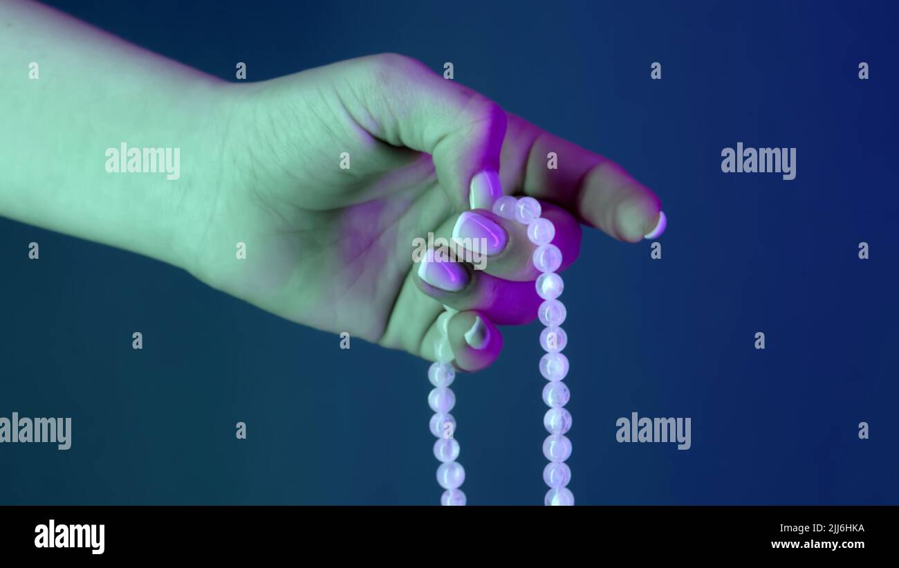 Frau betet und hält mala-Perlen in der Hand für Zählungen während Mantra-Meditationen. Dame auf blauem Hintergrund. Spiritualität, Religion, Gotteskonzept. Stockfoto