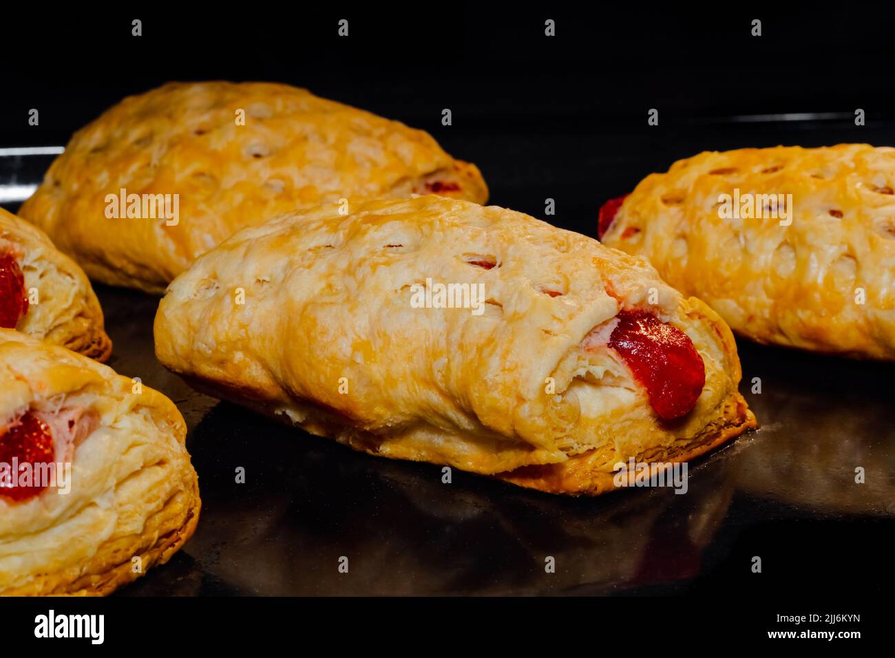 Gebackene hausgemachte Brötchen mit roter Erdbeermarmelade im Elektroofen Stockfoto