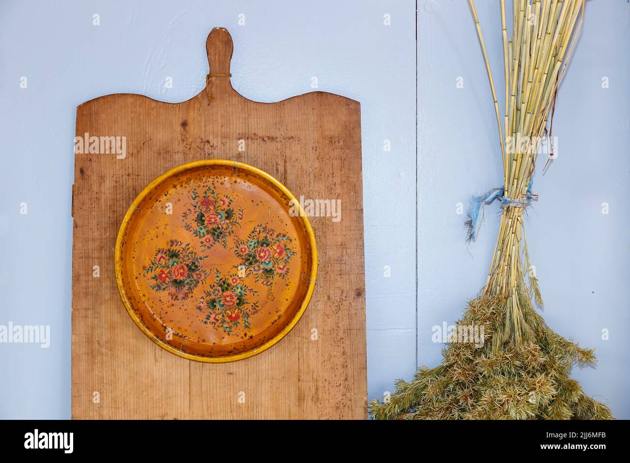 Gelbe Küchenobjekte und Dekor, Holzbrett und Teller mit dekorativen Ästen - blaue Platte Stockfoto