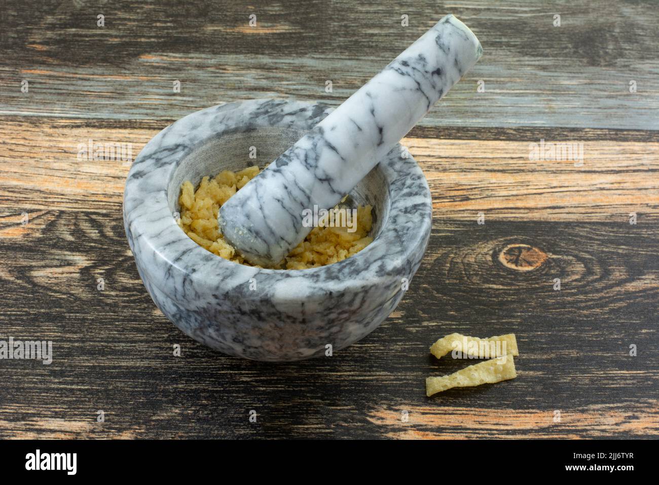 Zerkleinerte Wontonstreifen in Mörtel und Stößel auf dem Tisch, um knusprige Zutaten zum Kochen zu machen Stockfoto
