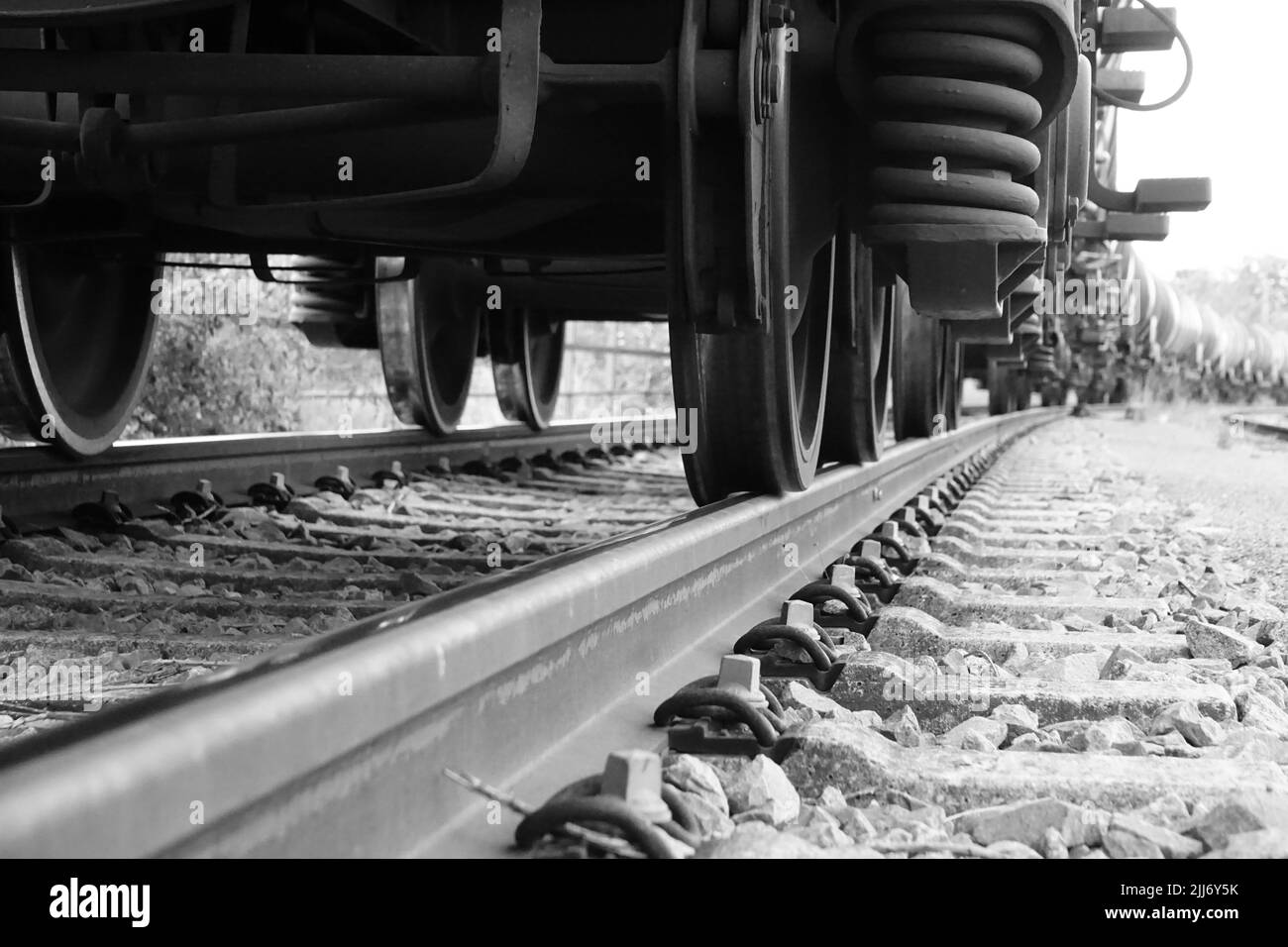 Eine Graustufenaufnahme der Gleise einer Eisenbahn mit einem sich bewegenden Zug Stockfoto