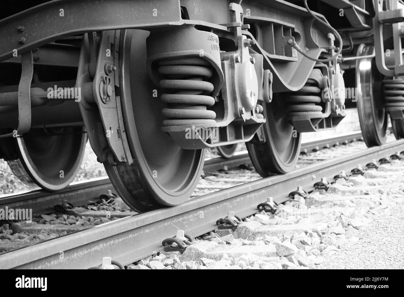 Eine Graustufenaufnahme der Gleise einer Eisenbahn mit einem sich bewegenden Zug Stockfoto