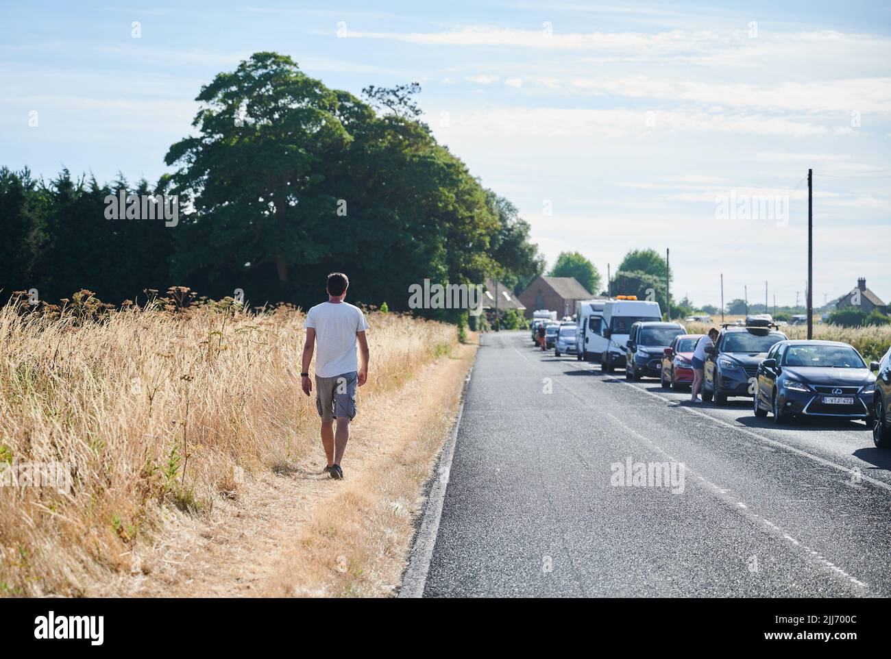 Folkstone, Großbritannien. 23.. Juli 2022. Ein Mann geht neben der Straße, die zum Eurotunnel in Folkestone führt. Zu Beginn der Ferien in Großbritannien stecken Reisende bis zu fünf Stunden in Staus, um an die Grenze zu gelangen. Medienberichten zufolge beschuldigen britische Behörden Frankreich für die Verzögerung der Grenzkontrollen. Quelle: Annette Riedl/dpa/Alamy Live News Stockfoto