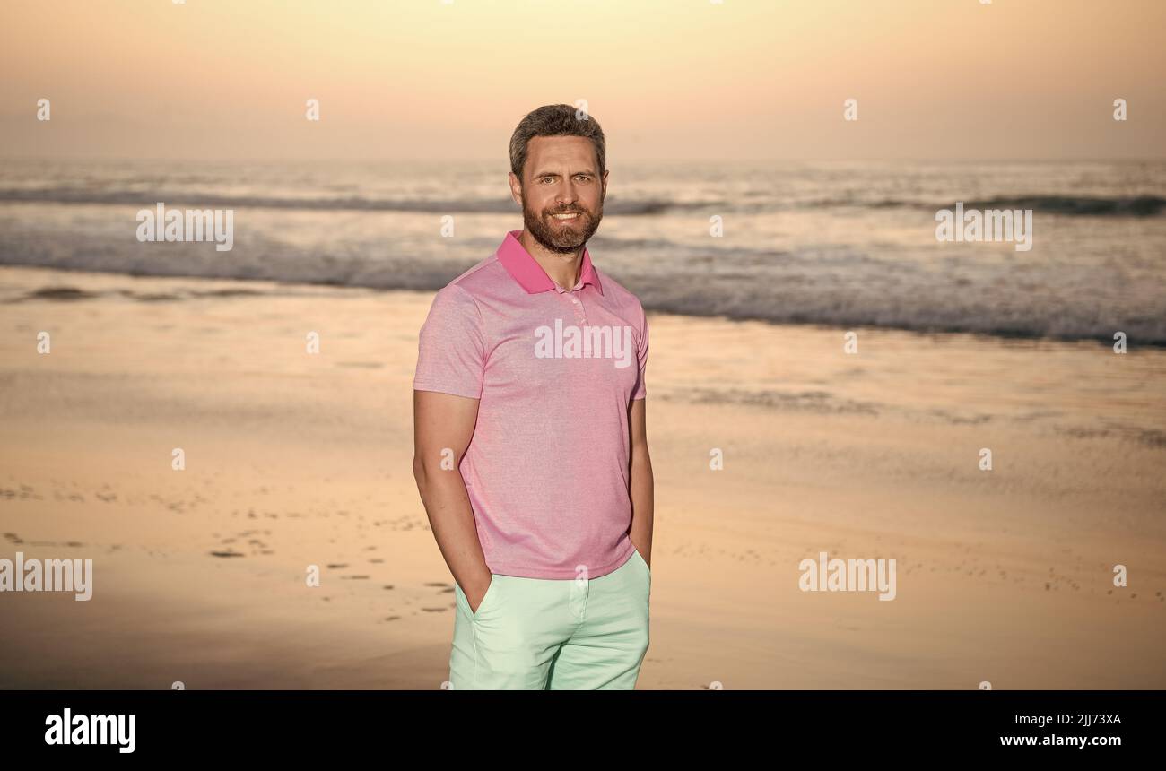 kaukasischer Kerl am Sonnenaufgangsstrand. Bärtiger Mann im Hemd. Sommermode-Stil. Sommerurlaub Stockfoto