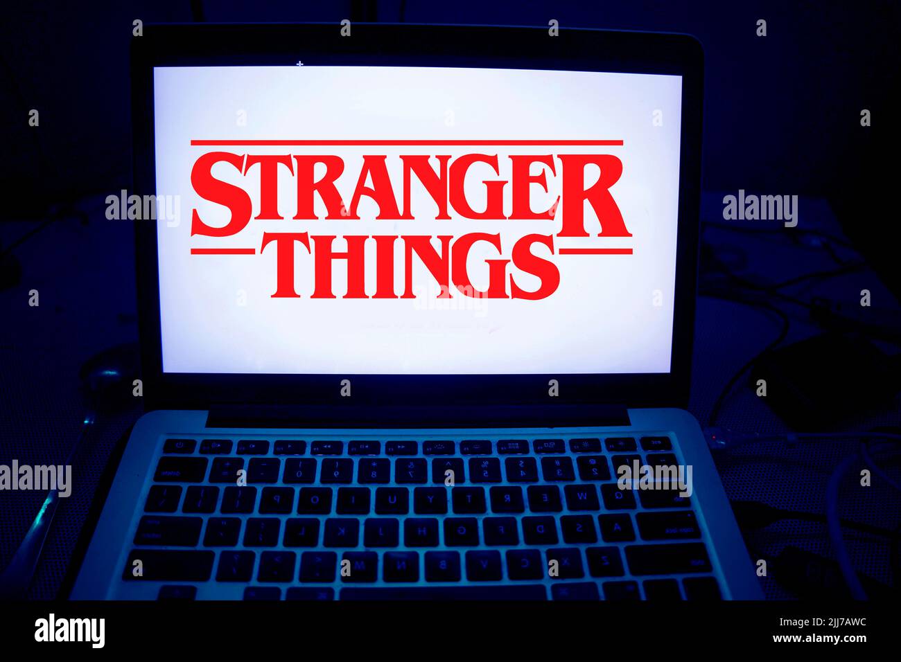 Eine eindrucksvolle Kinoaufnahme, inspiriert von „Stranger Things“, mit dem legendären roten Neon-Titellogo vor einem dunklen, stürmischen Hintergrund. Dieses Edito Stockfoto