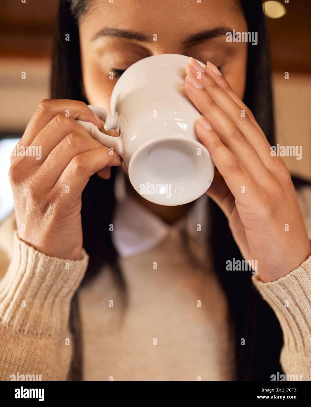 Es ist alles, was ich brauche, um durch den Tag zu kommen. Eine junge Frau, die eine Tasse Kaffee trinkt, während sie zu Hause sitzt. Stockfoto