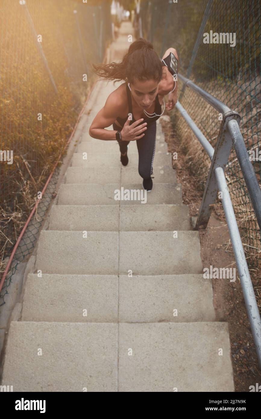 Weibliche Athletin, die morgens eine Treppe im Freien hochläuft. Sportliche junge Frau, die ein kräftiges körperliches Training absolviert. Stockfoto