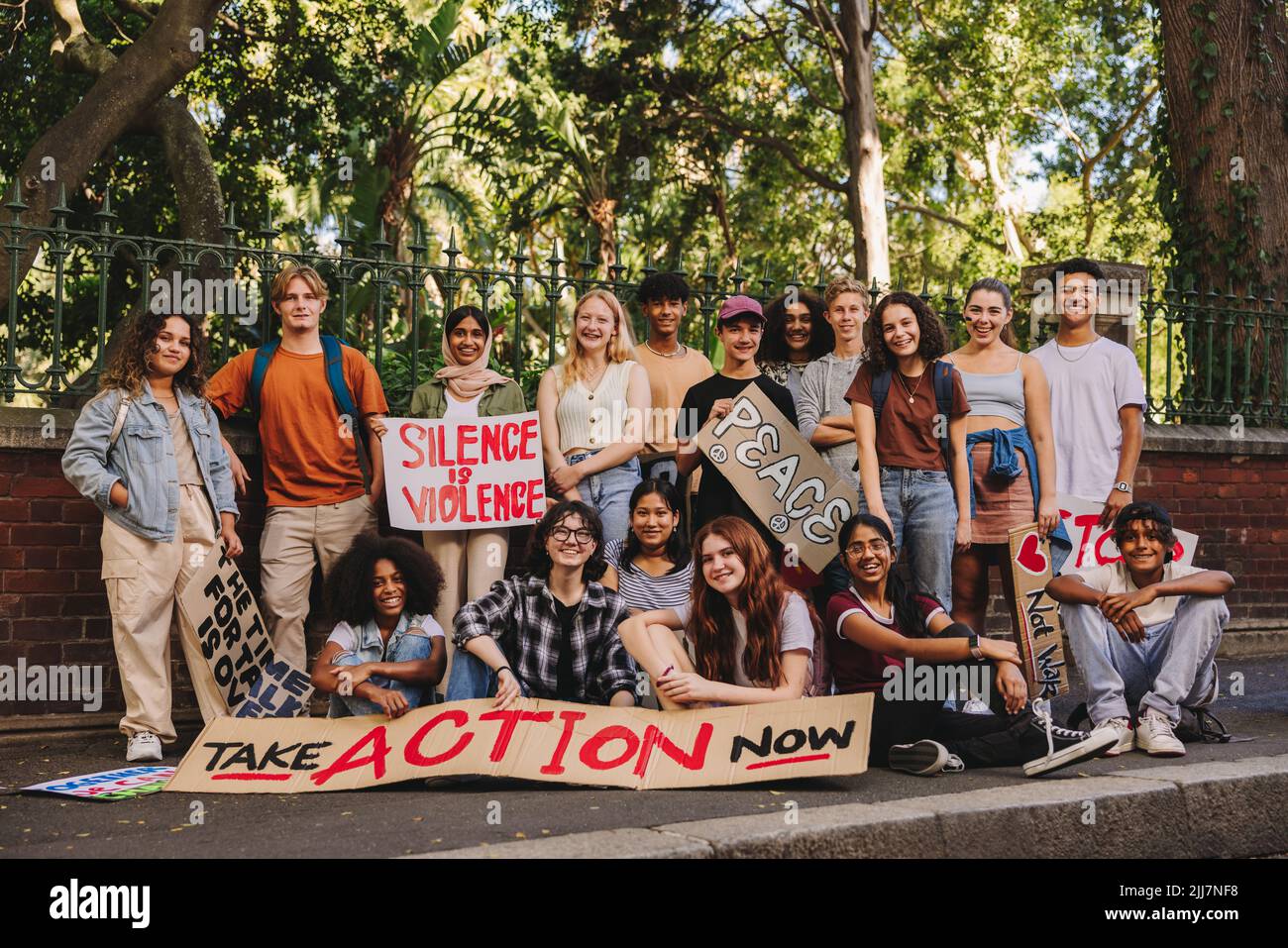 Friedensbewegung der Generation Z. Eine Gruppe multiethnischer Jugendaktivisten lächelt der Kamera zu, während sie Anti-Kriegs-Plakate und Banner zeigt. Frohes junges Peo Stockfoto