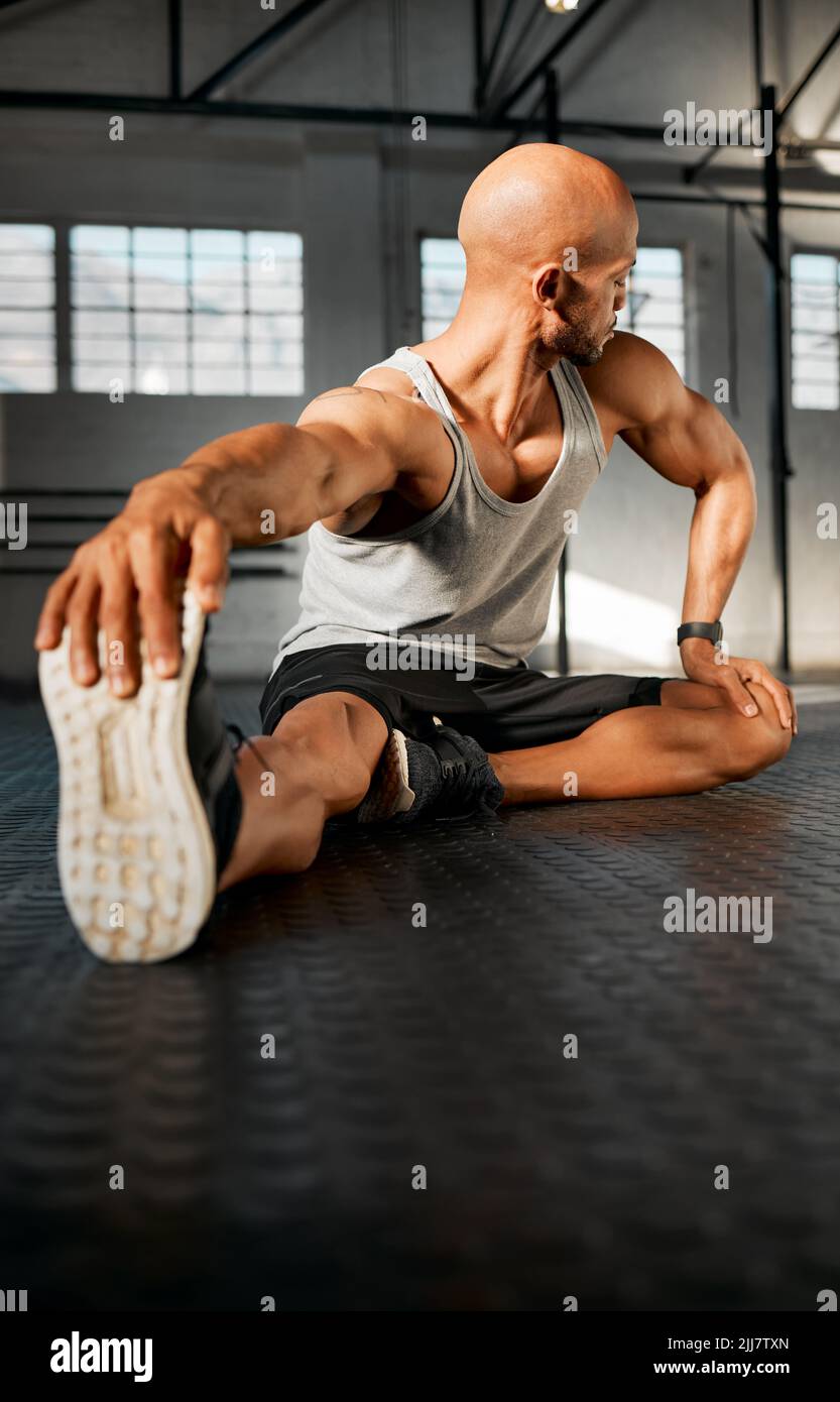 Der gesamte Körper ist ein Muskel. Ein junger Mann, der seine Beine vor einem Training streckt. Stockfoto