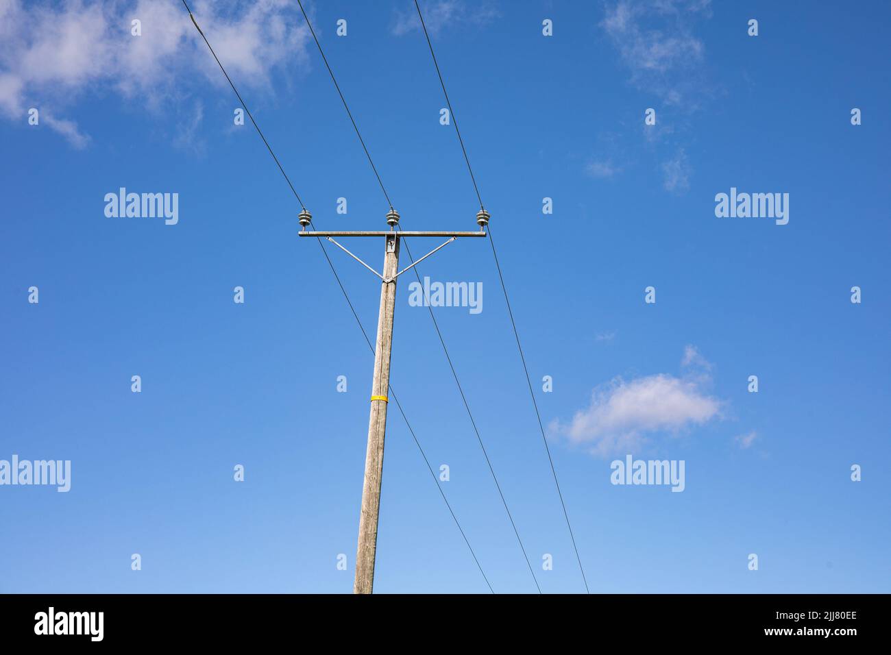 Alte hölzerne Pfosten oder elektrische Stange gegen blauen Himmel Stockfoto