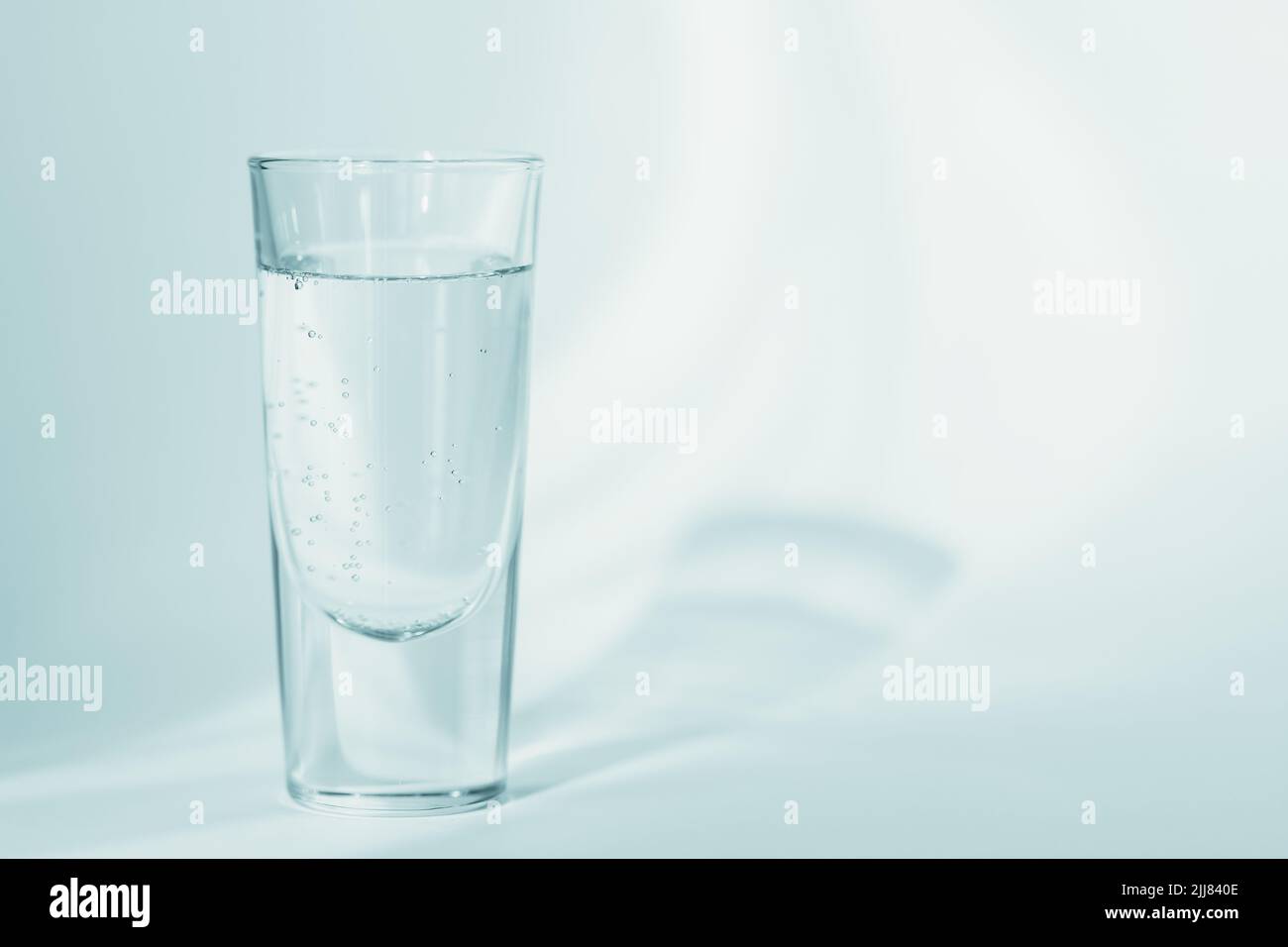 Glas sauberes Mineralwasser auf hellblauem Hintergrund Stockfoto
