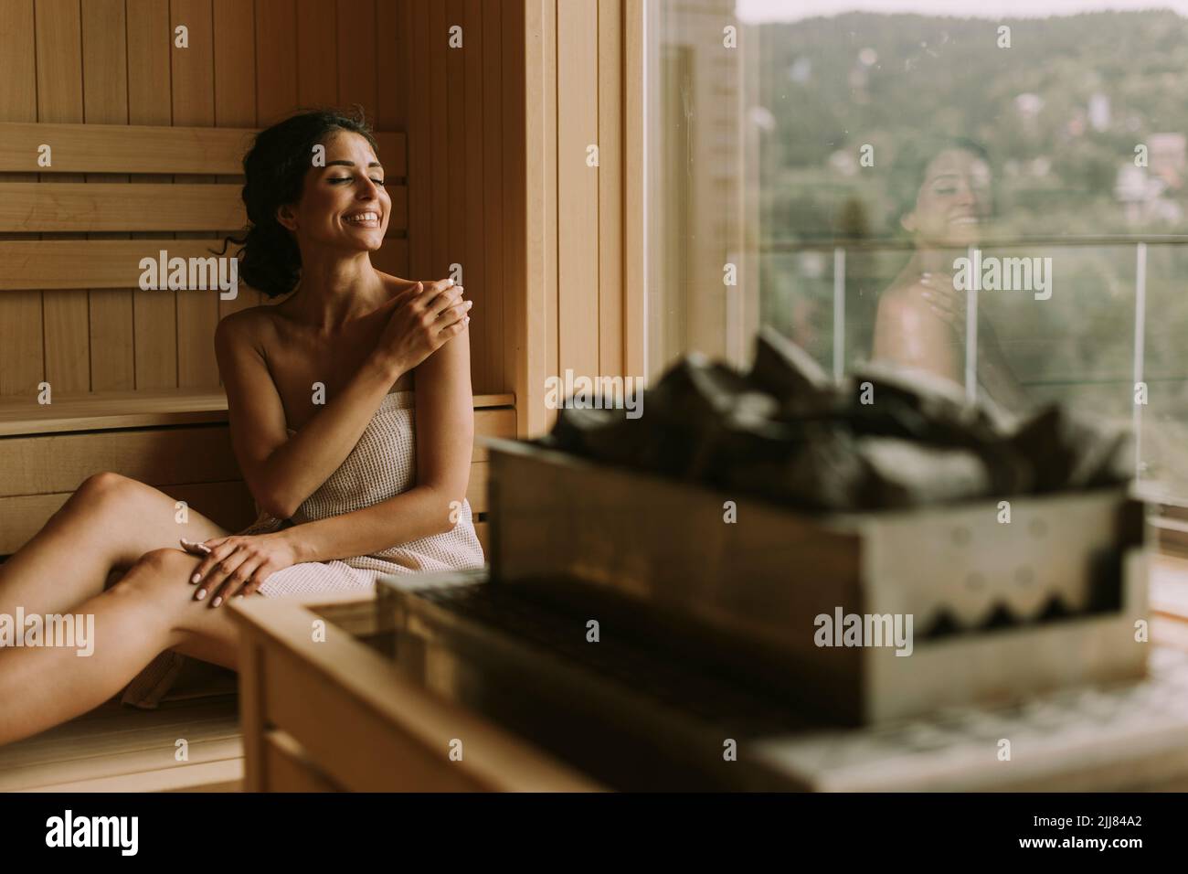 Attraktive junge Frau, die sich in der Sauna entspannt Stockfoto