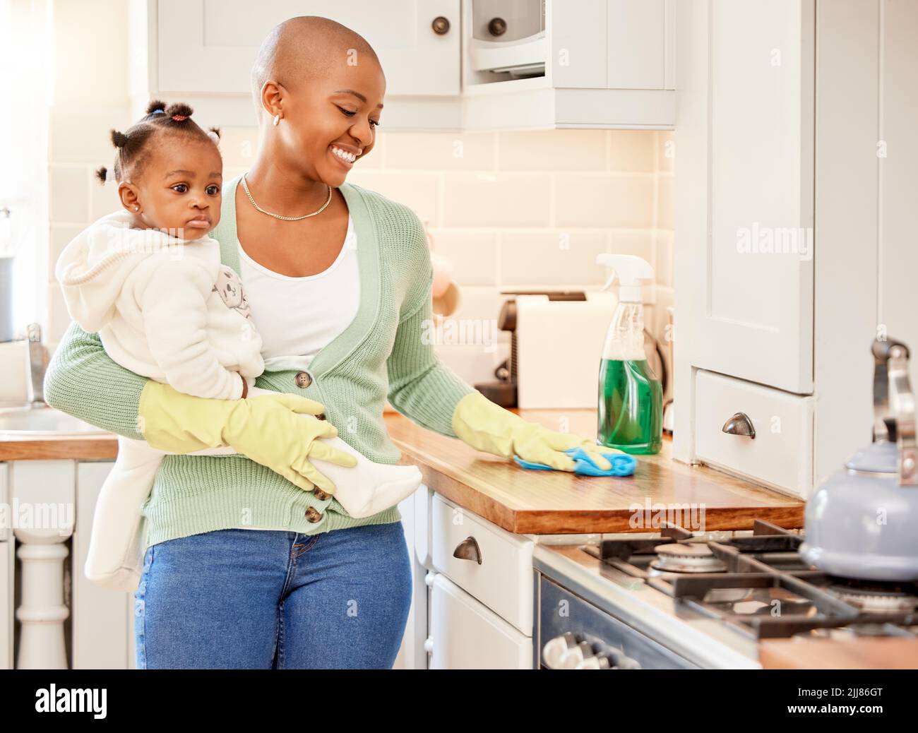 Sein Arbeitstag. Eine attraktive junge Frau trägt ihre Tochter, während sie zu Hause die Arbeit verrichten. Stockfoto