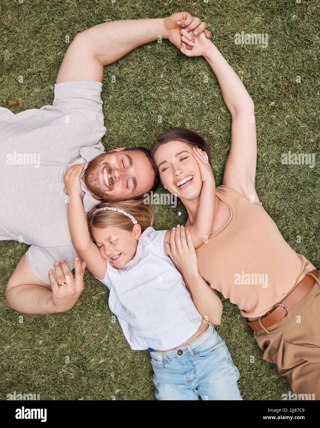 Waren eine glückliche Familie. High-Angle-Aufnahme einer jungen Familie, die zu Hause im Garten auf dem Gras liegt und sich verklebt. Stockfoto