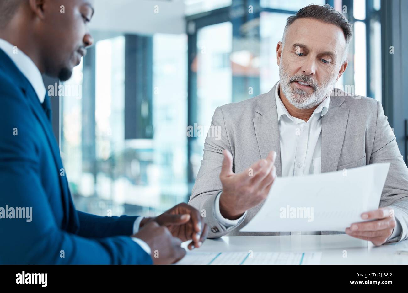 Diese Zahlen sehen gut aus für mich. Zwei Geschäftsleute diskutieren Schreibarbeit in einem modernen Büro. Stockfoto