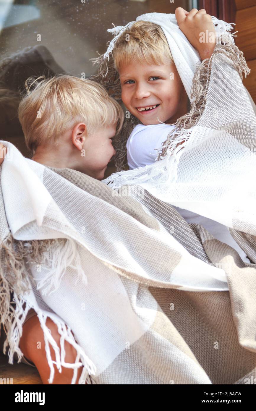 Zwei Brüder umarmen sich und haben gemeinsam Spaß unter einem warmen Karli. Stockfoto