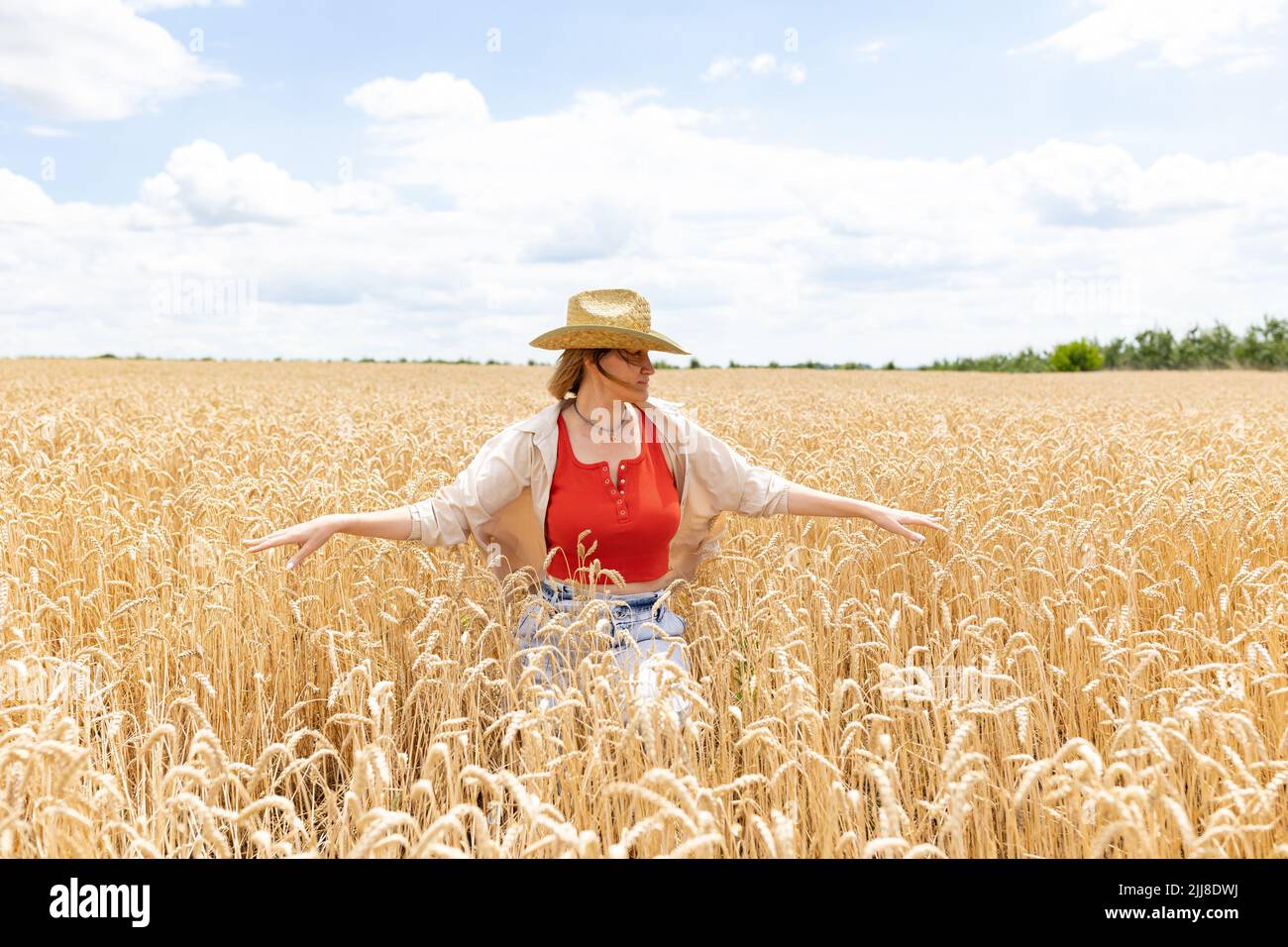 Frau in einem Hut sitzt in einem Feld von gelben Gold Weizenfeld. Glückliche Frau in der Natur zu Fuß. Stockfoto