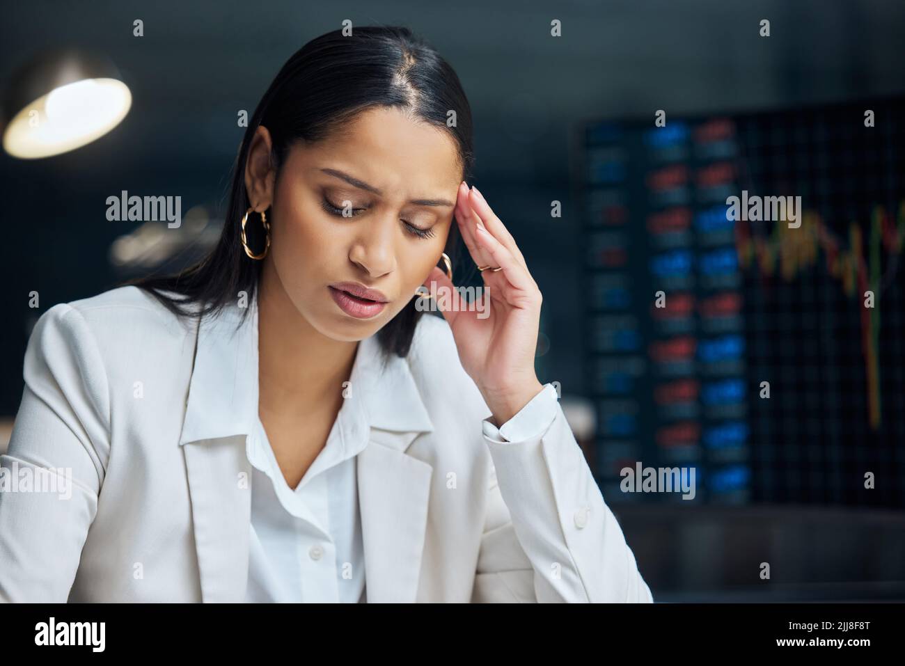 Ich muss herausfinden, woher ich mehr Geld bekomme. Eine attraktive junge Geschäftsfrau, die nachts allein in ihrem Büro sitzt und sich gestresst fühlt. Stockfoto