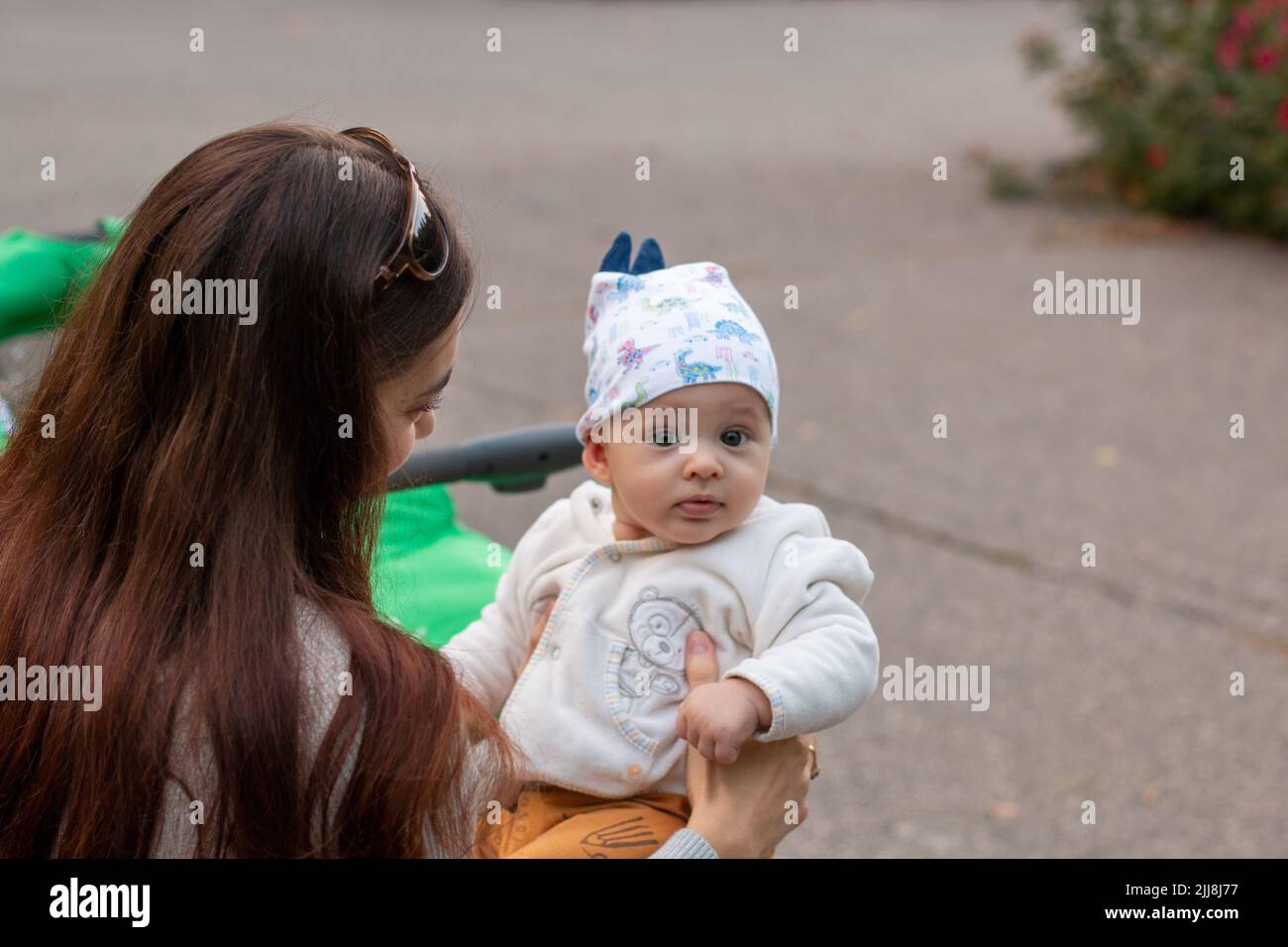 Junge Mutter hält unschuldiges Baby in liebevollen Händen draußen Stockfoto