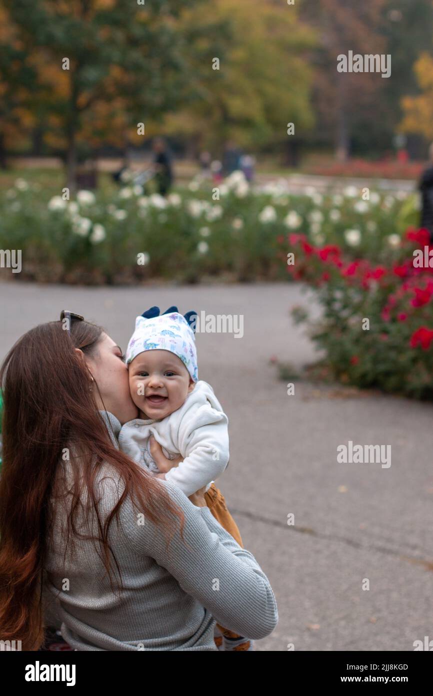 Mutter umarmte und küsste ihr kleines glückliches Baby draußen Stockfoto