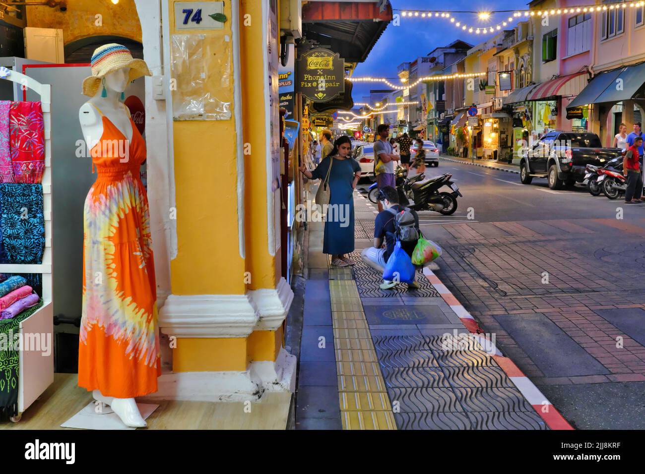 Die Abenddämmerung fällt an der Thalang Road in der Altstadt von Phuket Town, Thailand; links: Eine der modischen kleinen Boutiquen, die ihre Waren zeigen Stockfoto