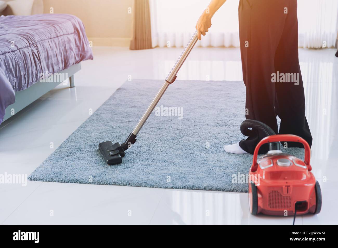 Hausfrau Reinigung Staub das Haus Saugen Sie den Teppich im Schlafzimmer in den Morgen. Maid mit Technologie sauber Haus Housekeeping Konzept. Stockfoto