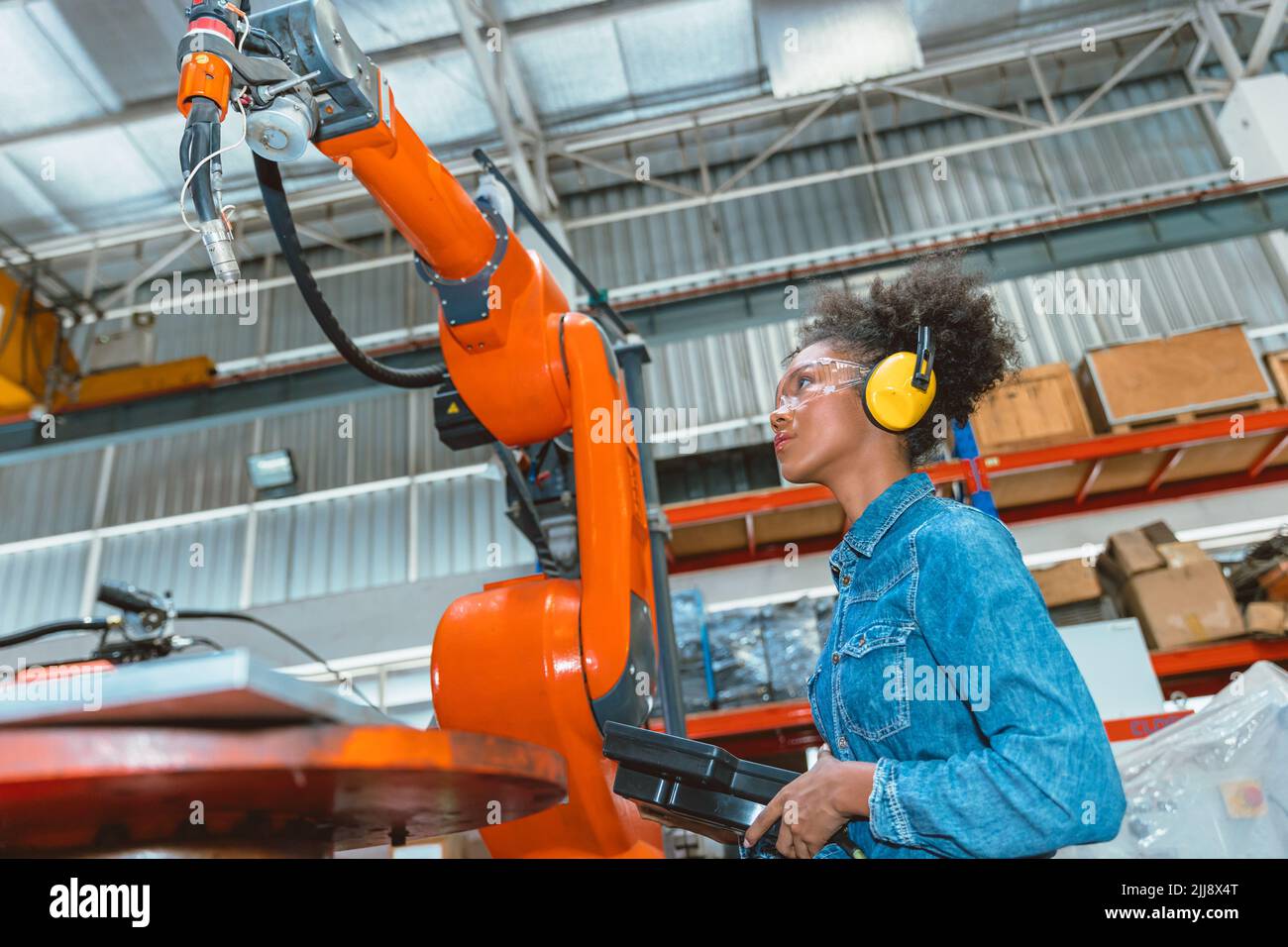 Ingenieur intelligente Frau Arbeiter arbeitet Programmierung Roboter Schweißmaschine. Schwarz teen Mädchen arbeiten im Voraus moderne Fabrik. Stockfoto