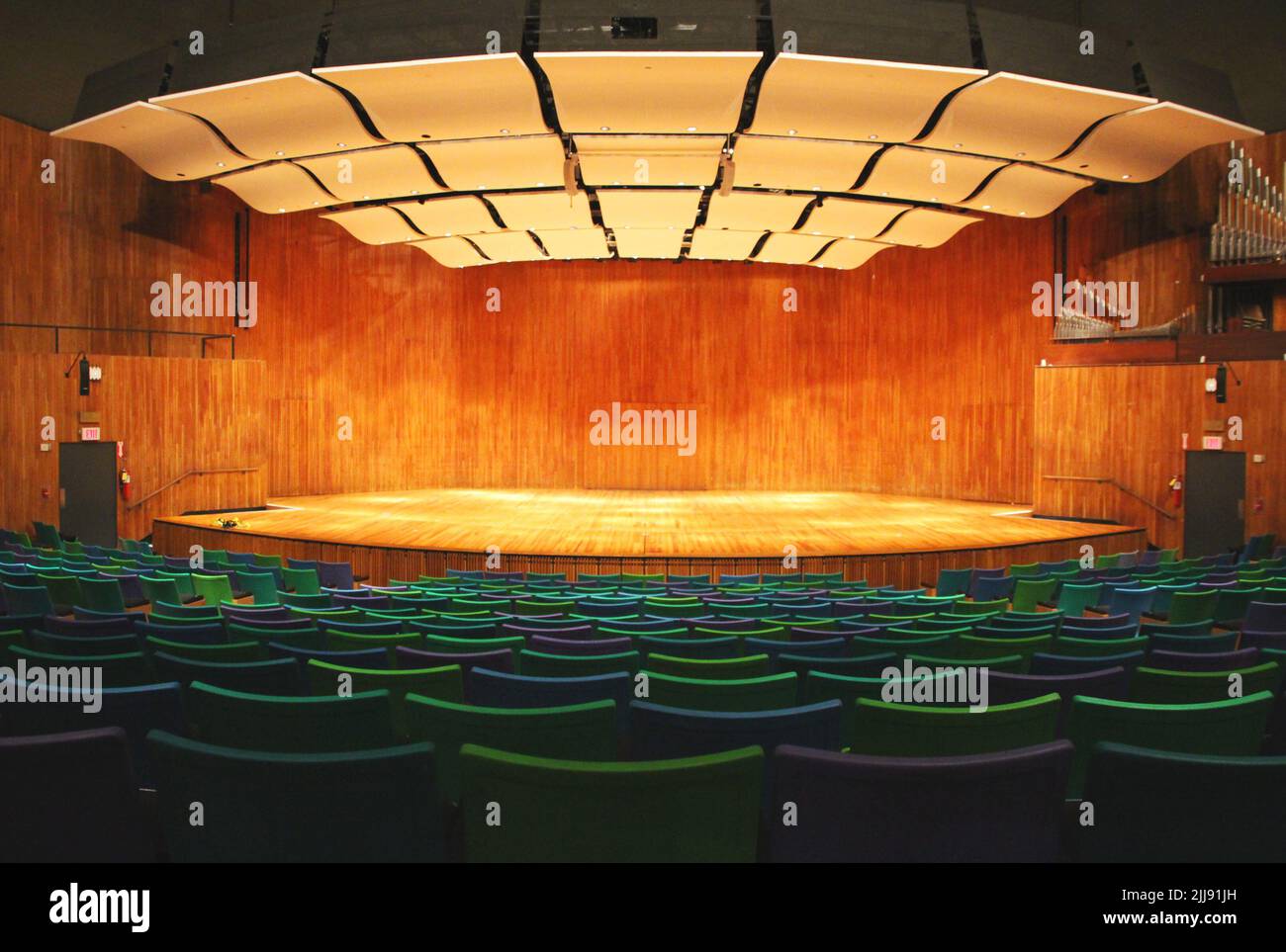 Vorderansicht von den Tribünen einer leeren Innenbühne, mit grünen Sitzen und den Lampen an Stockfoto