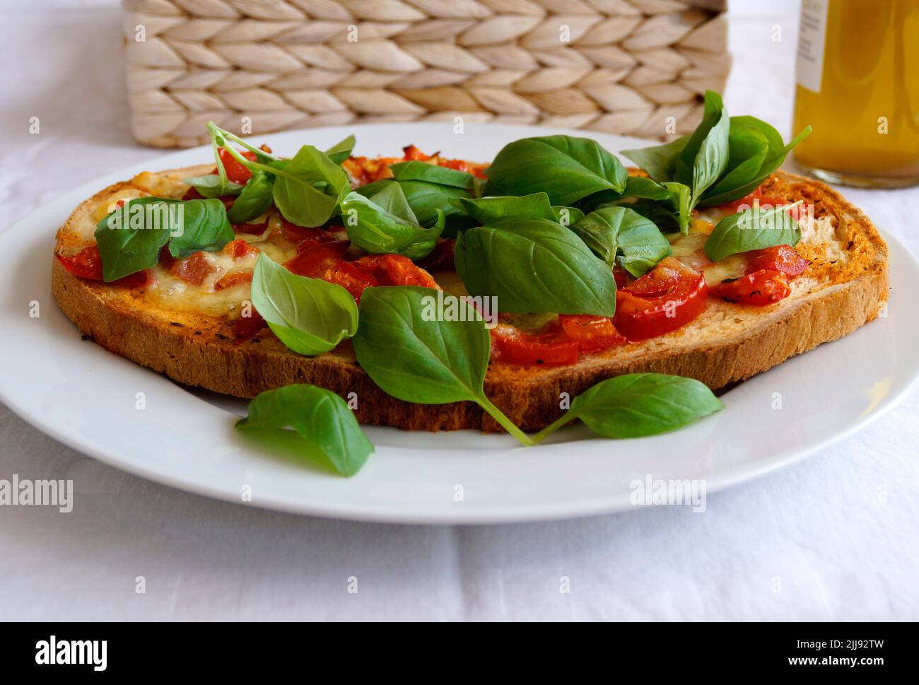 Köstliche große italienische Bruschetta mit Mozzarella, Knoblauch, Olivenöl und Basilikumblättern auf einem Teller Stockfoto