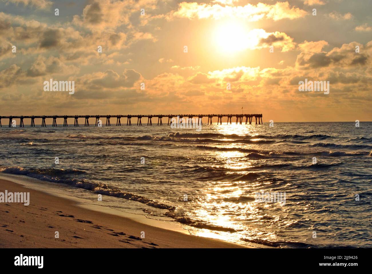 Goldener Sonnenaufgang über dem Pier am Pensacola Beach, Florida Stockfoto