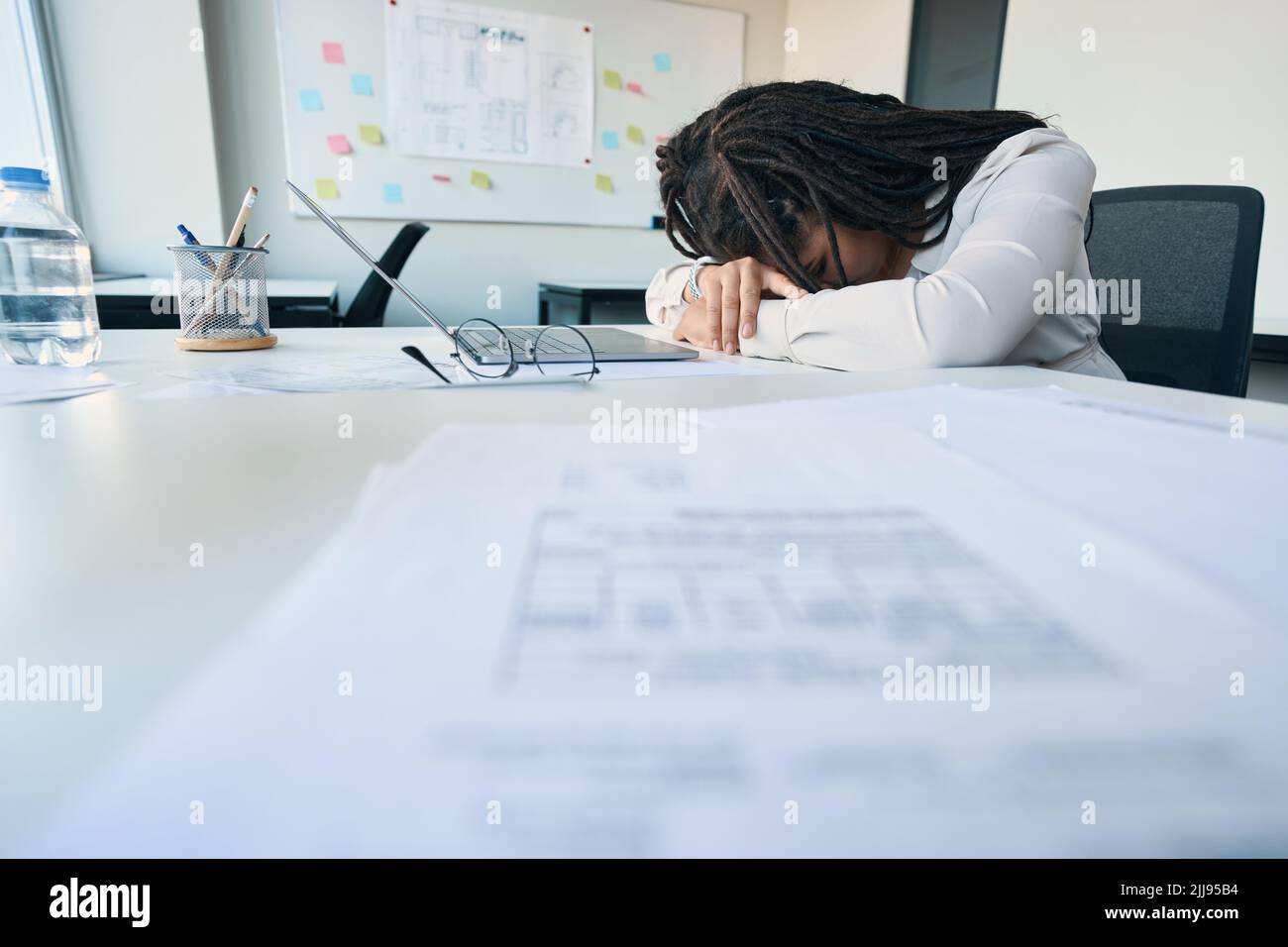 Müde Angestellte, die an ihrem Arbeitsplatz nippt Stockfoto