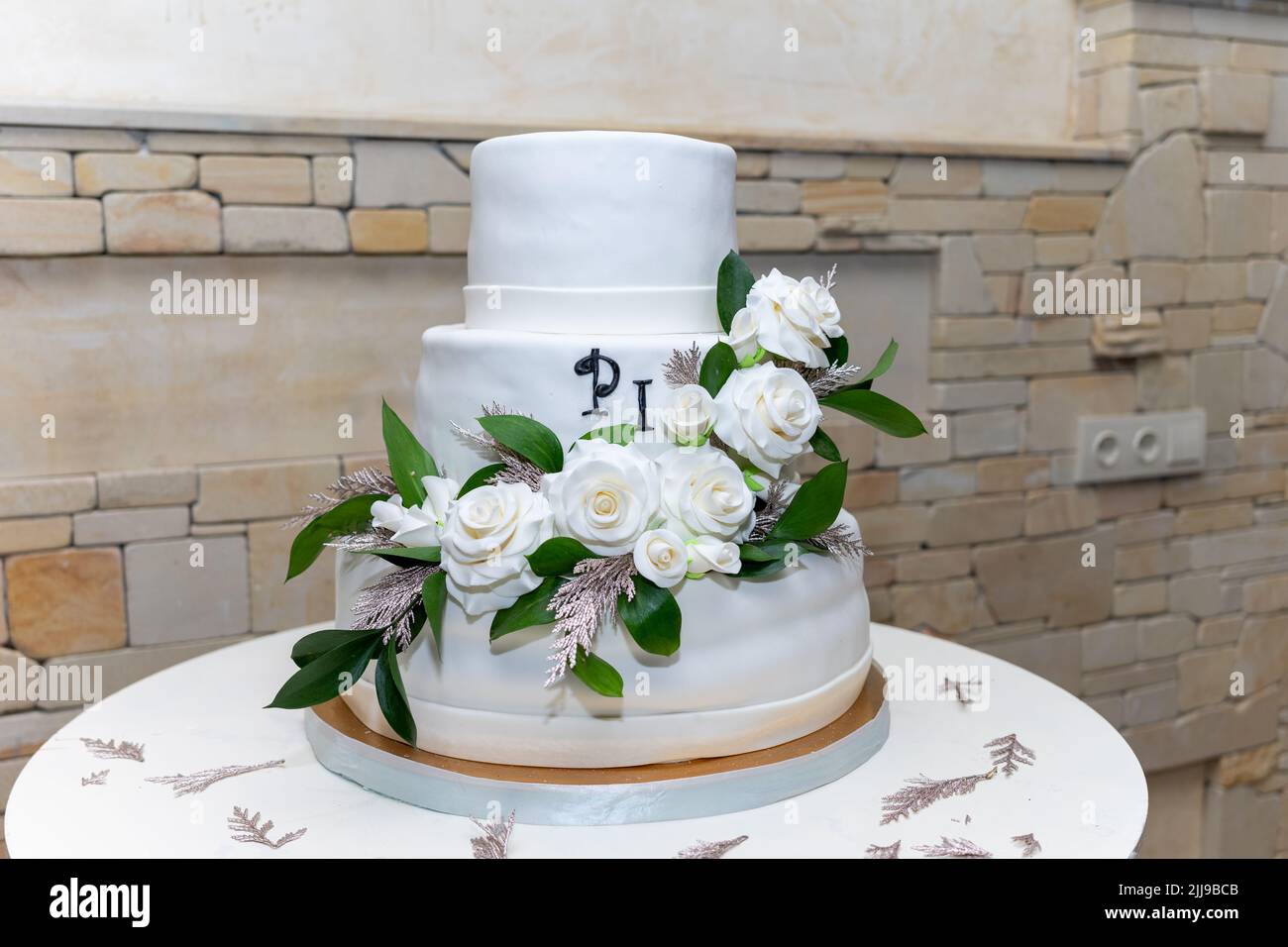 Schöne große Hochzeitstorte mit drei Etagen, dekoriert von zarten süßen Rosen. Weiße Hochzeitstorte mit drei Ebenen und weißen Rosen Stockfoto