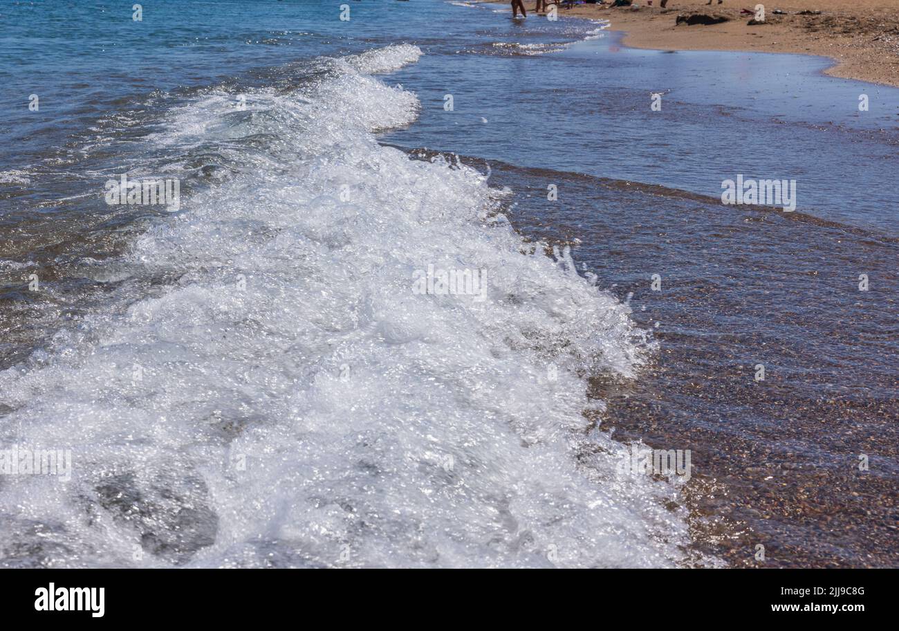 Schöner Blick auf die rollenden Wellen am Sandstrand des Mittelmeers. Stockfoto