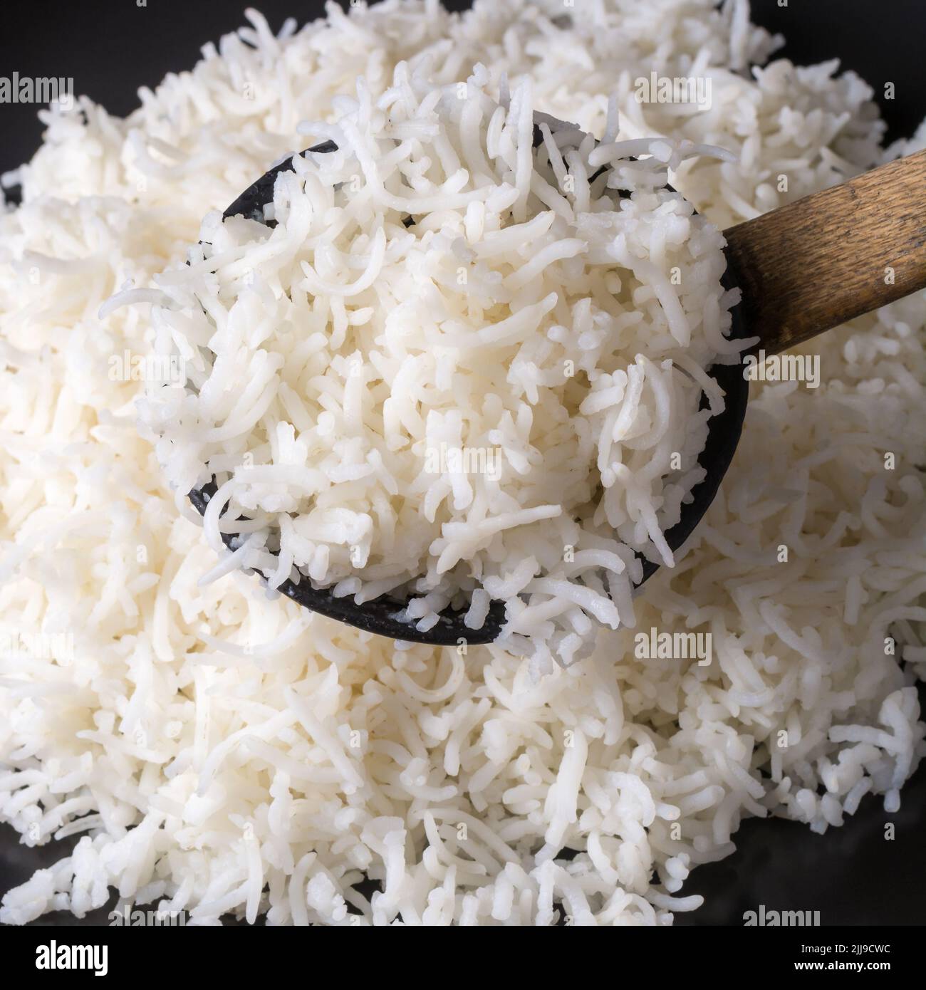 Holzlöffel voll gekochtem weißen Basmati-Reis, Nahaufnahme von frisch gekochtem langkörnigen aromatischen Reis, in geringer Schärfentiefe aufgenommen, Lebensmittelhintergrund Stockfoto