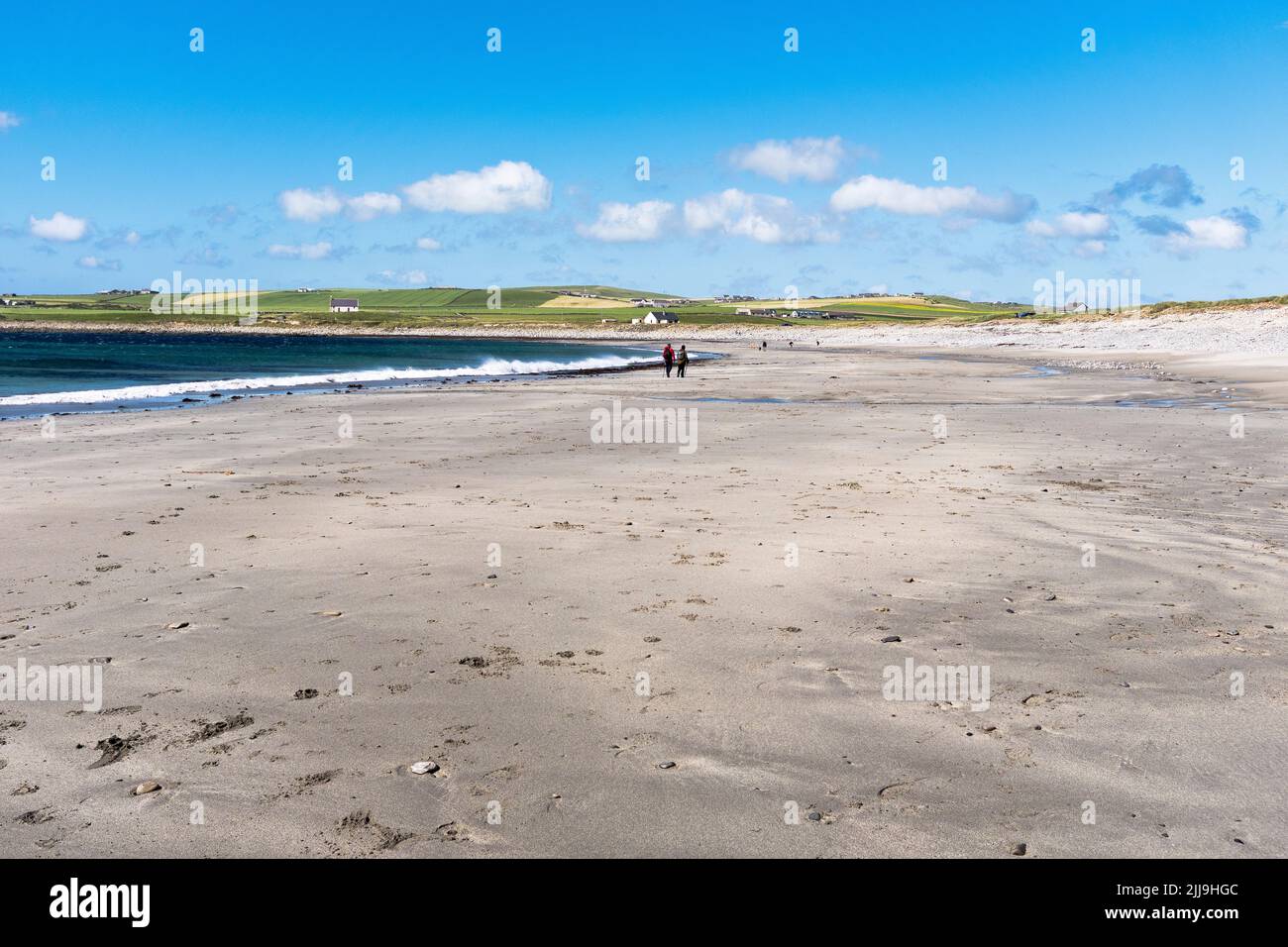 dh Skaill Bay SANDWICK ORKNEY Paar zu Fuß entlang Sandstrand blaues Meer Sommer Himmel Sand Stockfoto