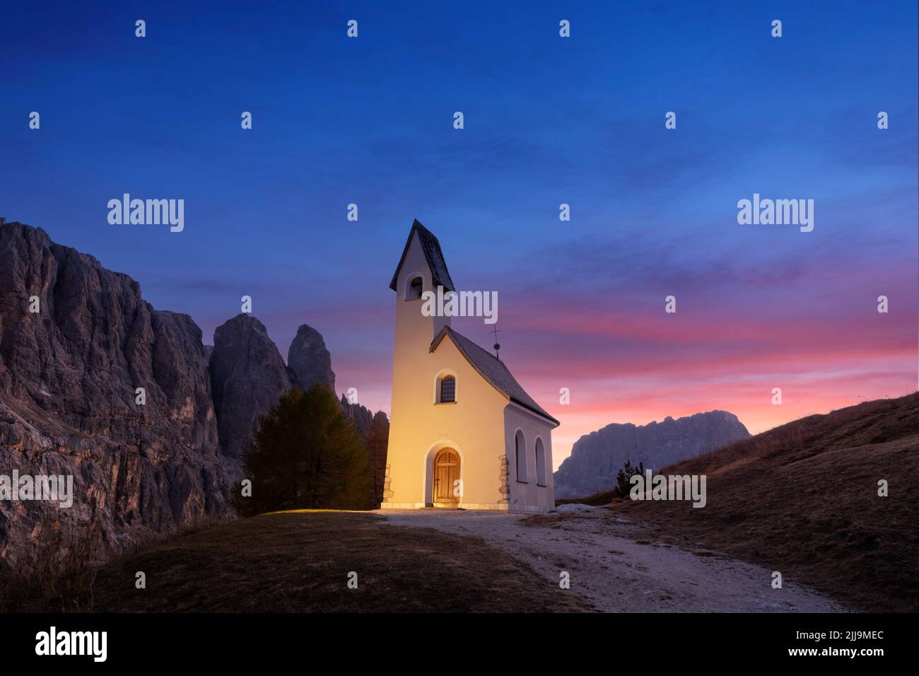 Unglaubliche Aussicht auf die kleine iIlluminated Chapel - Kapelle Ciapela am Grödner Pass, italienische Dolomiten Berge. Farbenfrohe Sonnenuntergänge in den Dolomiten, Italien. Landschaftsfotografie Stockfoto