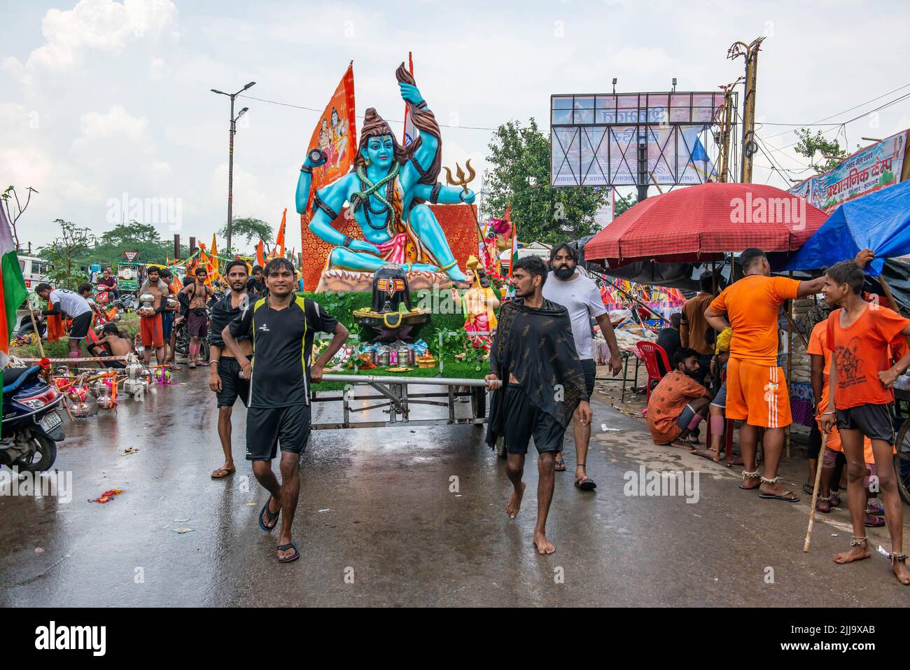 Kanwariyas ziehen einen Maha Kanwar, der als Lord Shiva geschmückt wird, während er heiliges Wasser trägt, das vom Ganga-Fluss vor dem Shivratri-Festival gesammelt wird, auf der Delhi Meerut-Straße in Ghaziabad. Der Monat Sravana (der vierte Monat des Hindu-Kalenders) ist Lord Shiva gewidmet. Während der jährlichen Monsunsaison tragen Tausende von safrangekleideten Pilgern Wasser aus dem Ganges in Haridwar, Gangotri oder Gaumukh und kehren in ihre Heimatorte zurück, wo sie später als Dankesgeste Abhisheka (Salbung) der Shivalingas in den lokalen Shiva-Tempeln durchführen. Stockfoto