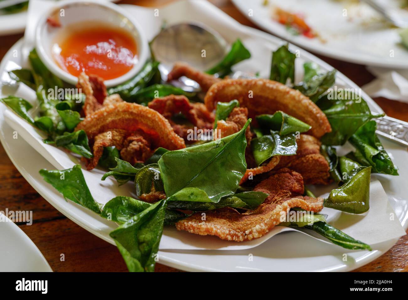 Dünn geschnittener knuspriger Schweinebauch mit Kaffir-Limettenblättern und würziger Sauce. Stockfoto
