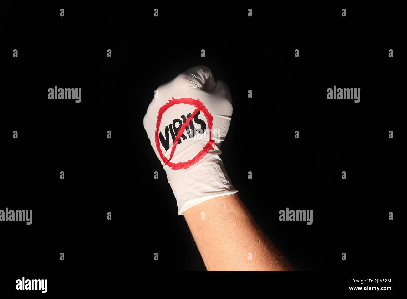 Faust in Einweghandschuh mit Anti-Virus-Zeichen vor schwarzem Hintergrund Stockfoto
