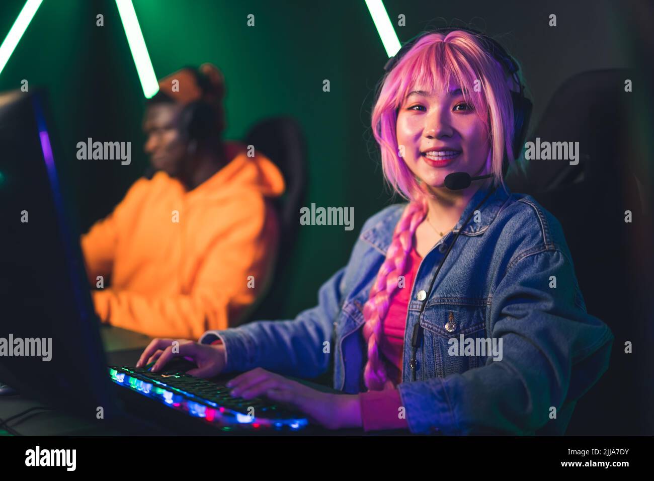 Müde fokussierte asiatische hübsche Mädchen mit einem langen rosa Zopf sitzen in einem Gaming-Stuhl während einer Online-Gaming-Meisterschaft, versuchen zu gewinnen. Hochwertige Fotos Stockfoto