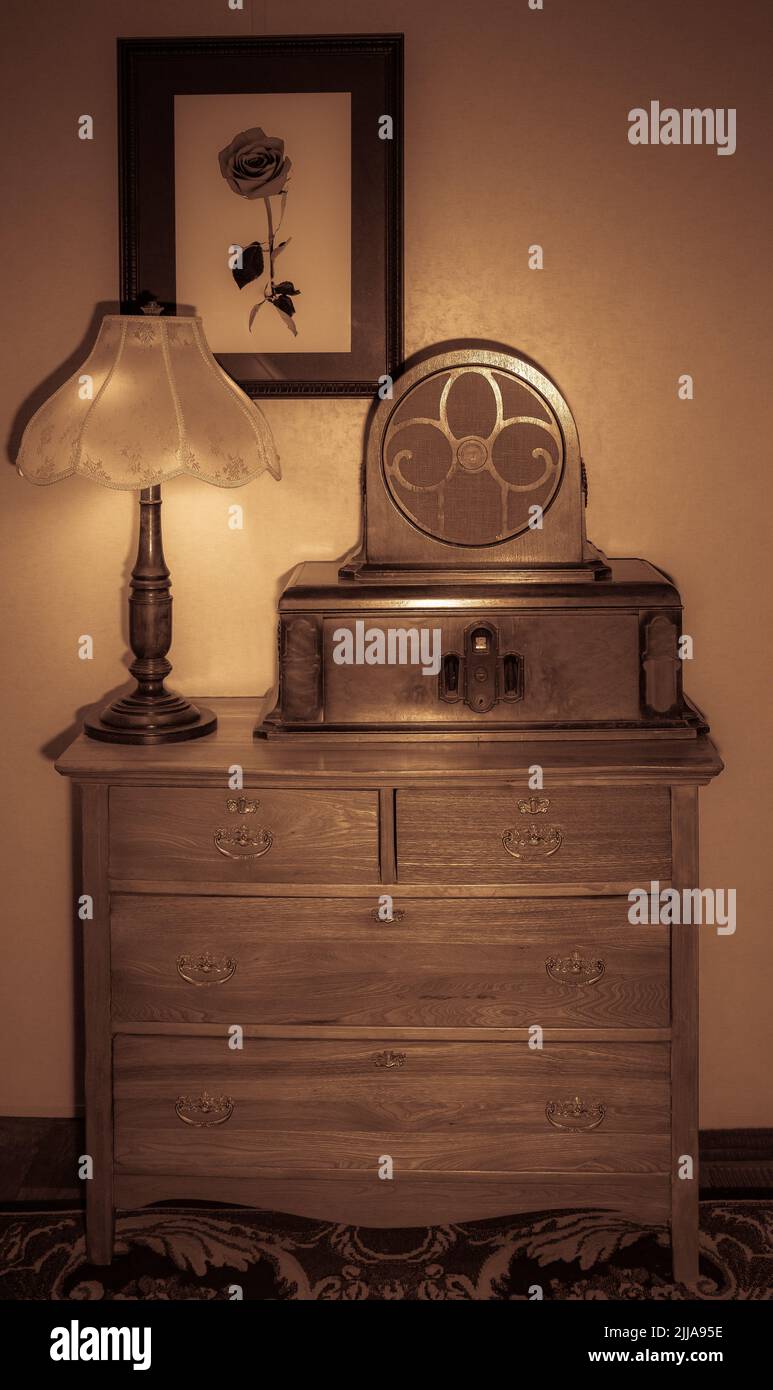 Catamount Lake am Pikes Peak. Antiquitätenradio neben einer antiken Lampe auf einer antiken Kommode mit einem Rosenfoto Stockfoto