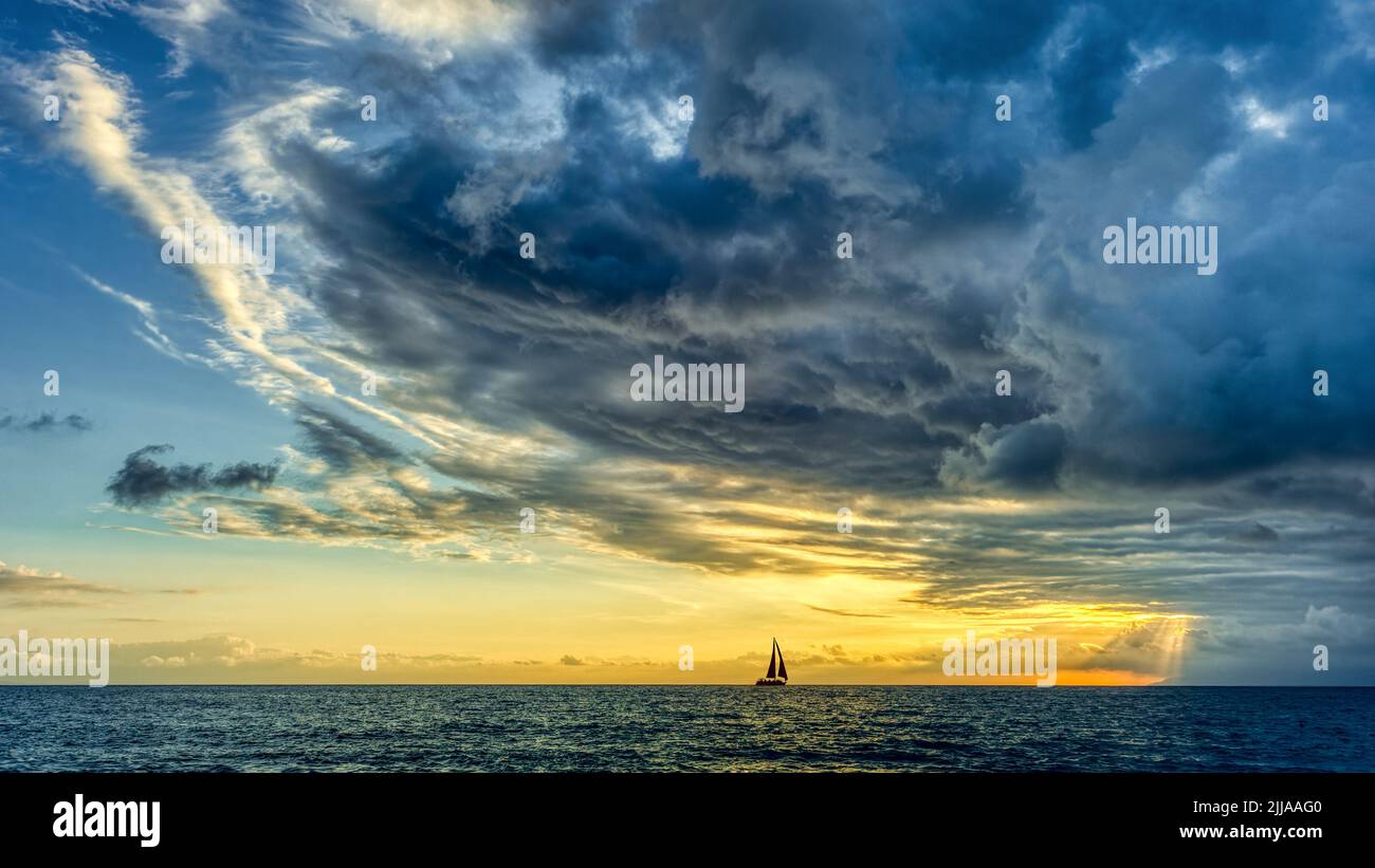 Ein Sturm droht über uns, als Sich Ein kleines Boot zum Shining Light bewegt Stockfoto