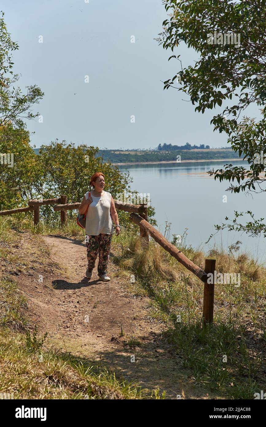 Eine reife hispanische Frau, die auf einem Touristenpfad im El Palmar Nationalpark, Entre Rios, Argentinien, spazierengeht. Konzepte: Naturtourismus, Naturschutzgebiete, Stockfoto