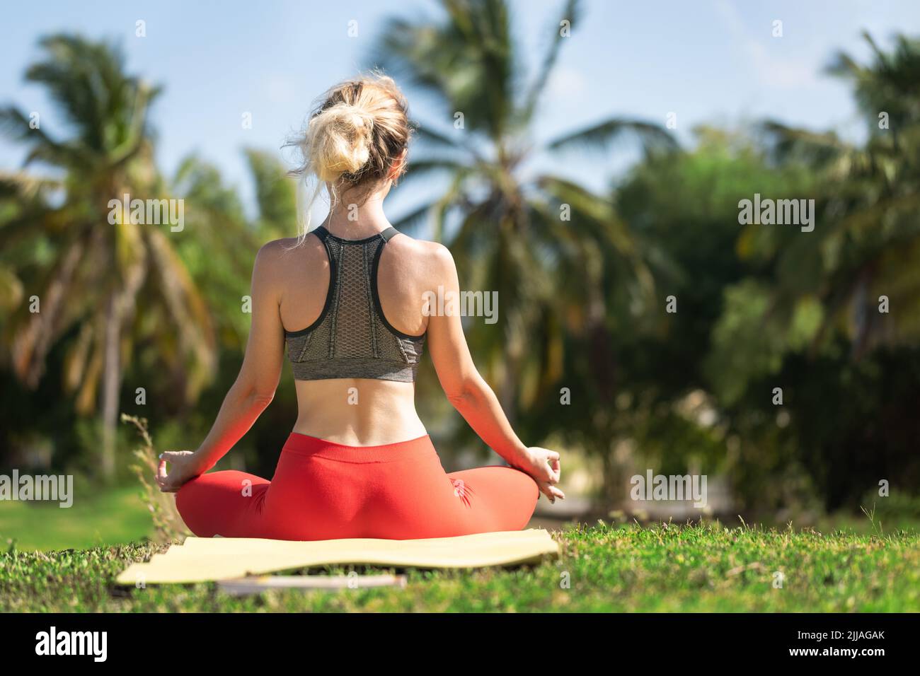 Eine junge Frau praktiziert Yoga an der Meeresküste während des Sonnenaufgangs. Stockfoto
