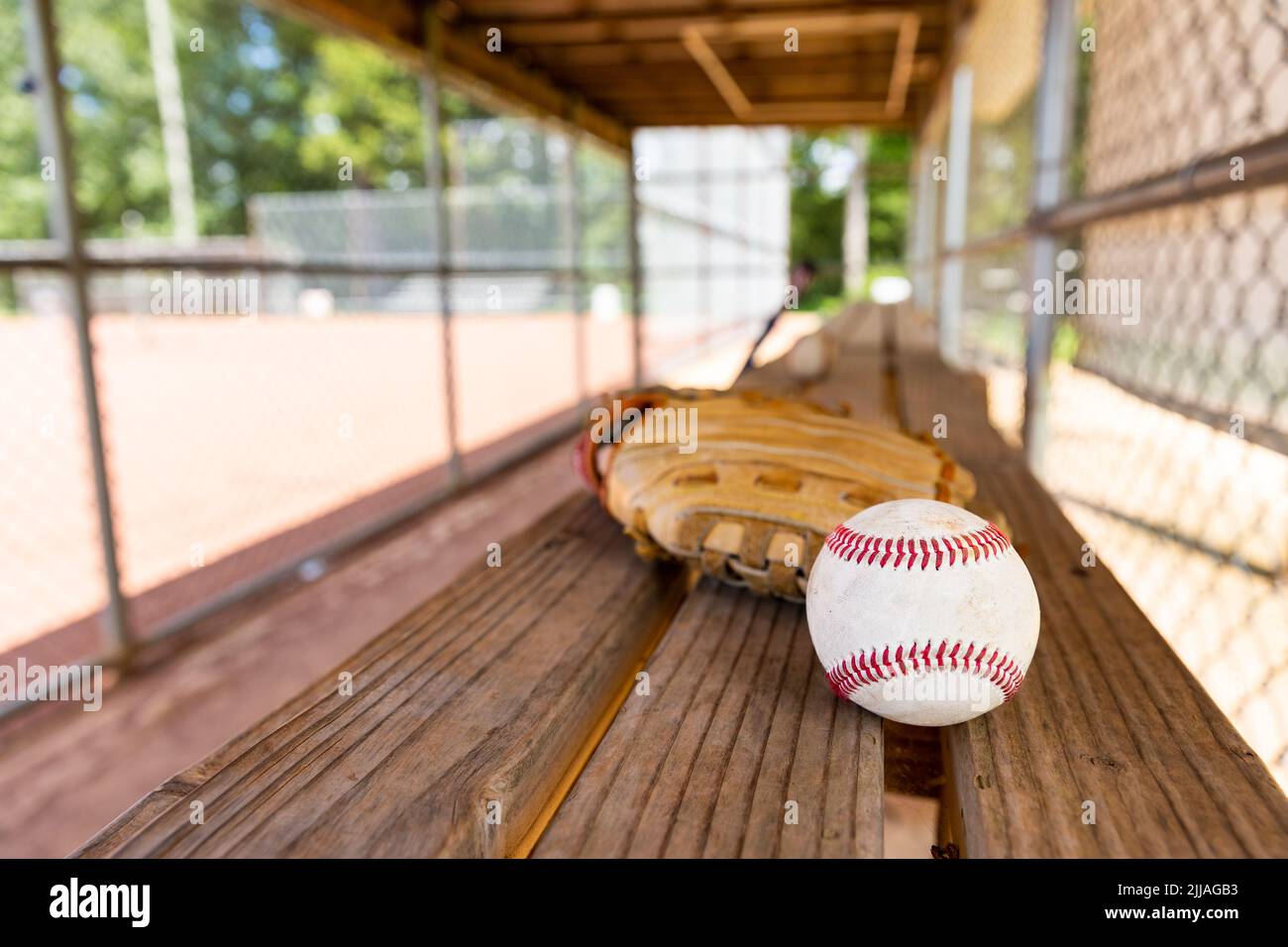 Baseballspiele und Handschuh auf der Dugout-Bank mit unscharfem Hintergrund Stockfoto