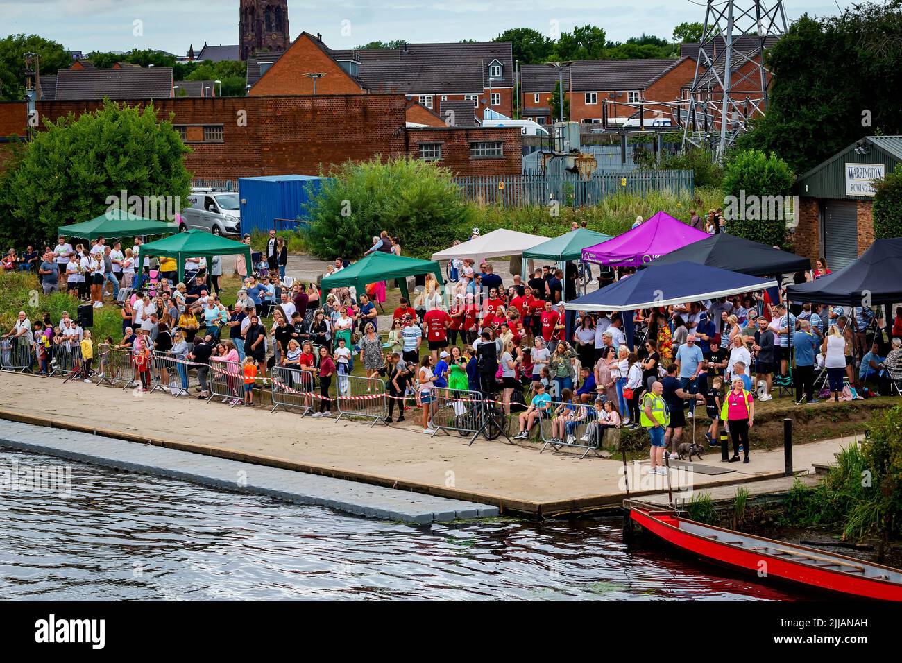 Zuschauer und Konkurrenten warten unter ihren Pavillons auf das Drachenboot-Rennen Stockfoto